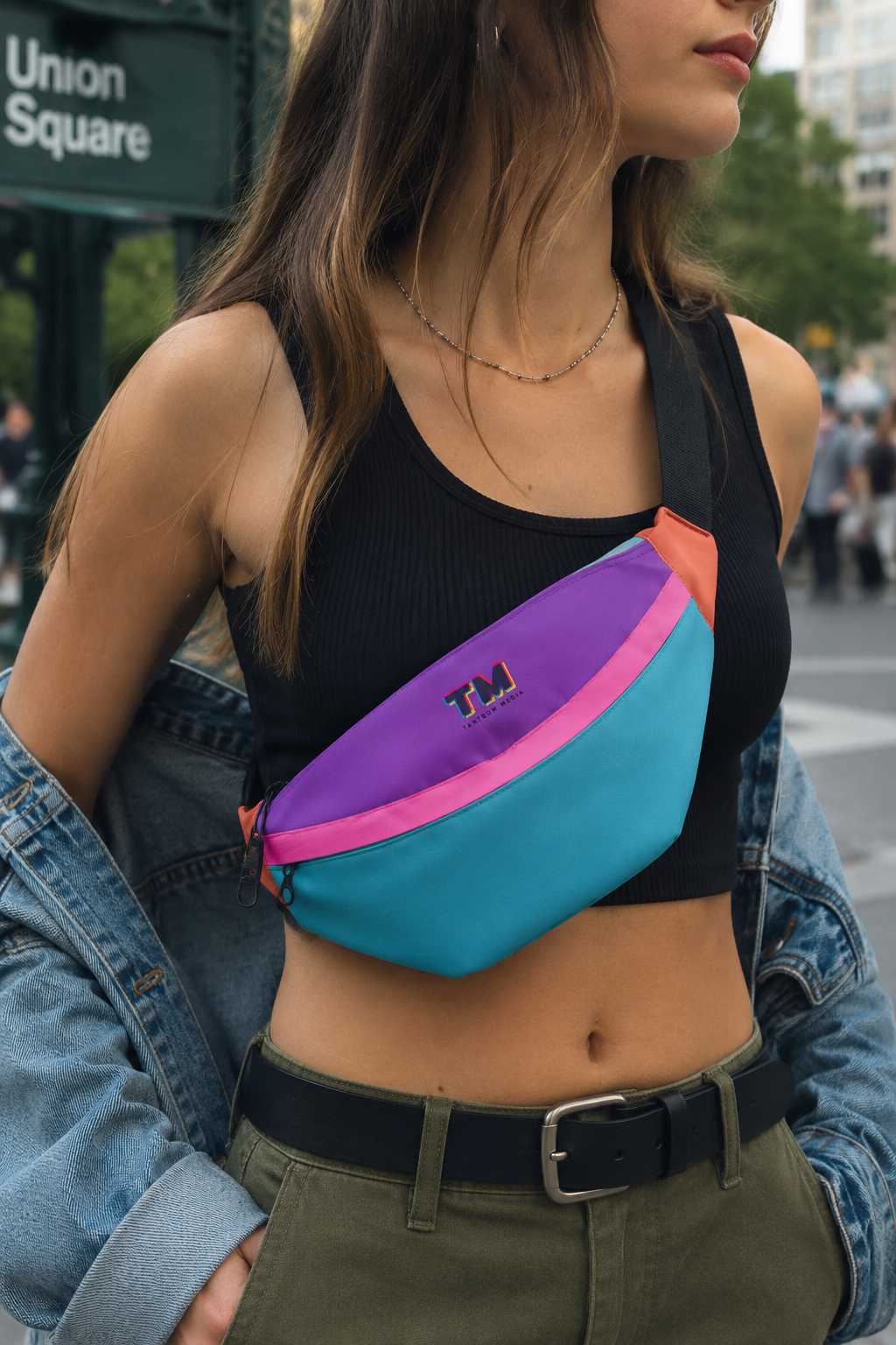 Woman wearing a multicolor fanny pack crossbody while walking through Union Square in New York City.