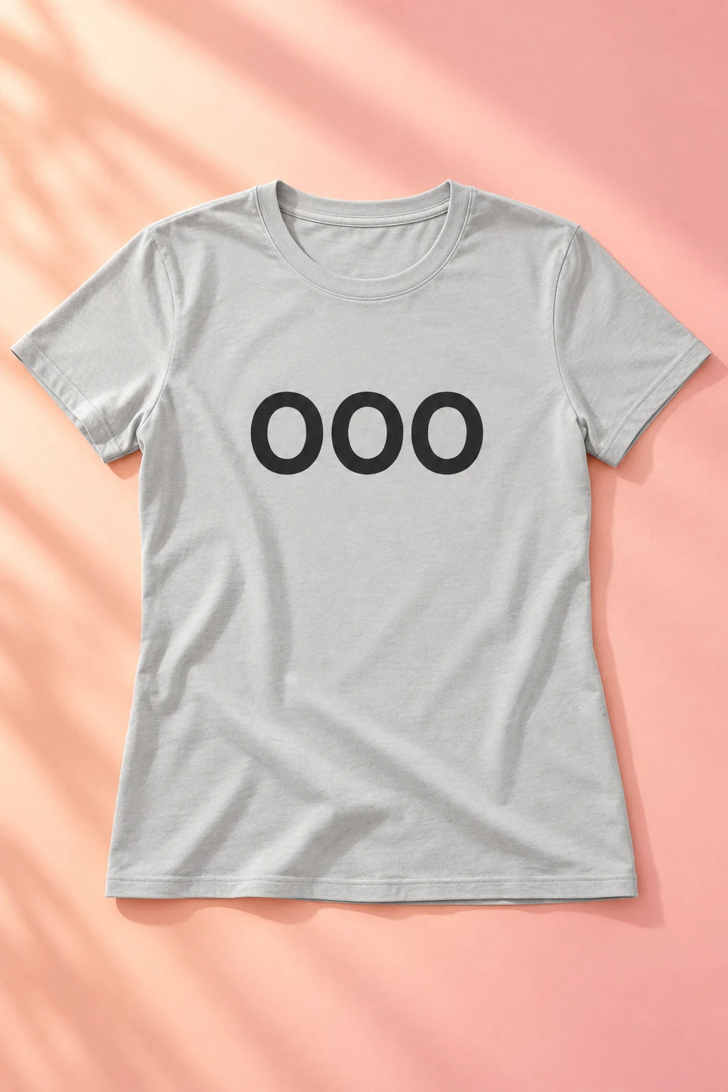 Light gray OOO T-shirt laid flat on a soft peach and blush background.