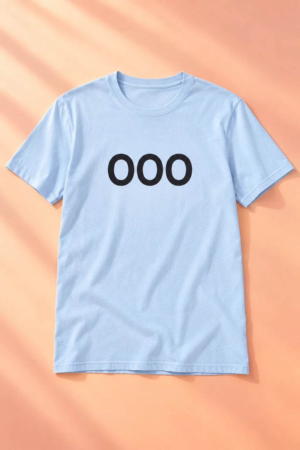 Light blue OOO T-shirt laid flat on a soft peach gradient background.