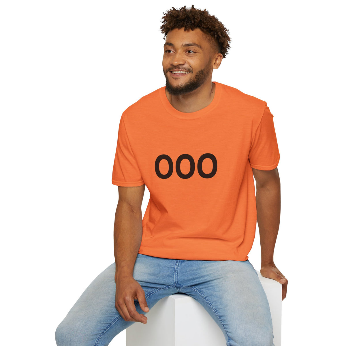 Seated man wearing an orange OOO graphic T-shirt with light blue jeans.