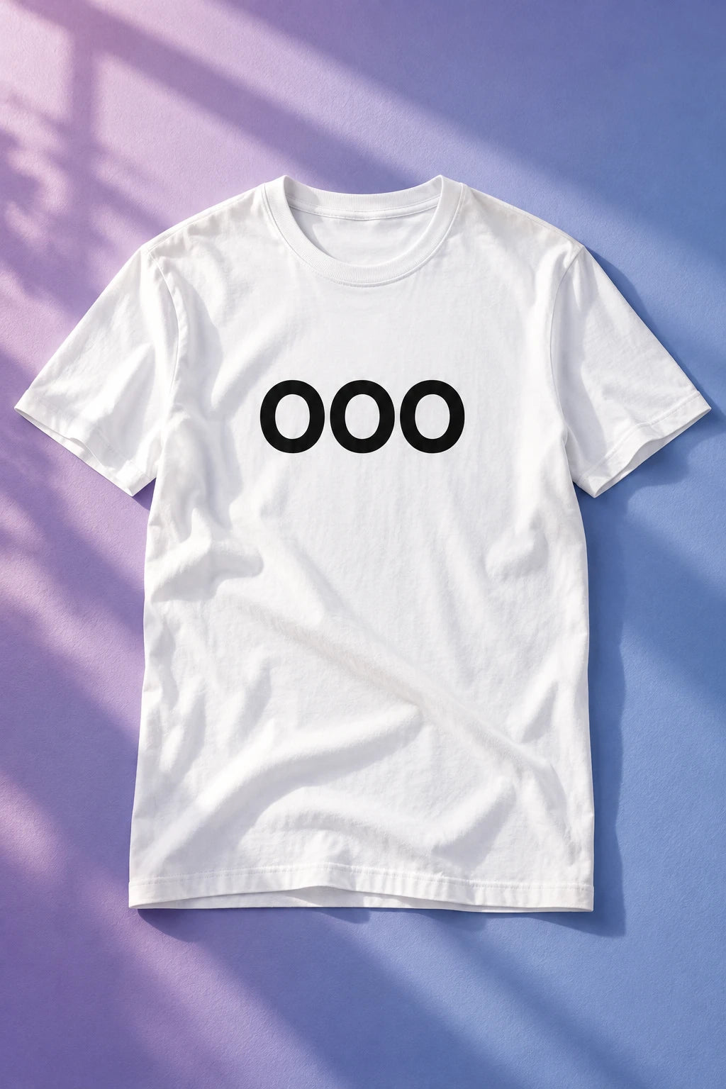 White OOO T-shirt laid flat on a lavender and blue background with diagonal window shadows.