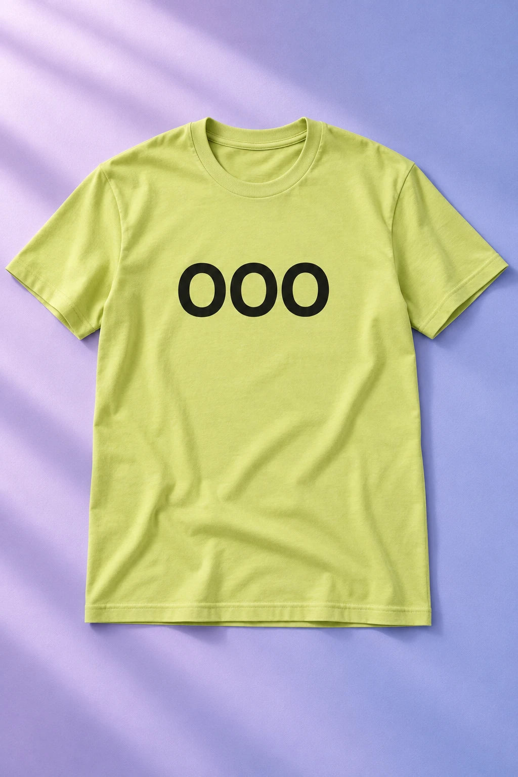 Pale yellow-green OOO T-shirt laid flat on a lavender and periwinkle background.