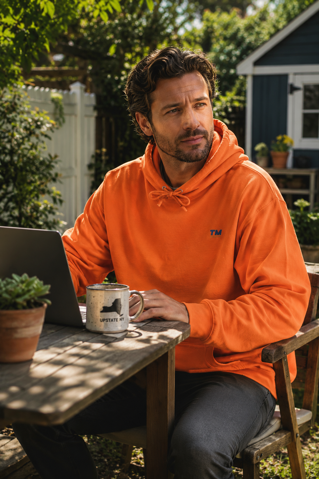 Male millennial working from his backyard in upstate New York wearing the Tantrum Media EcoSmart orange hoodie