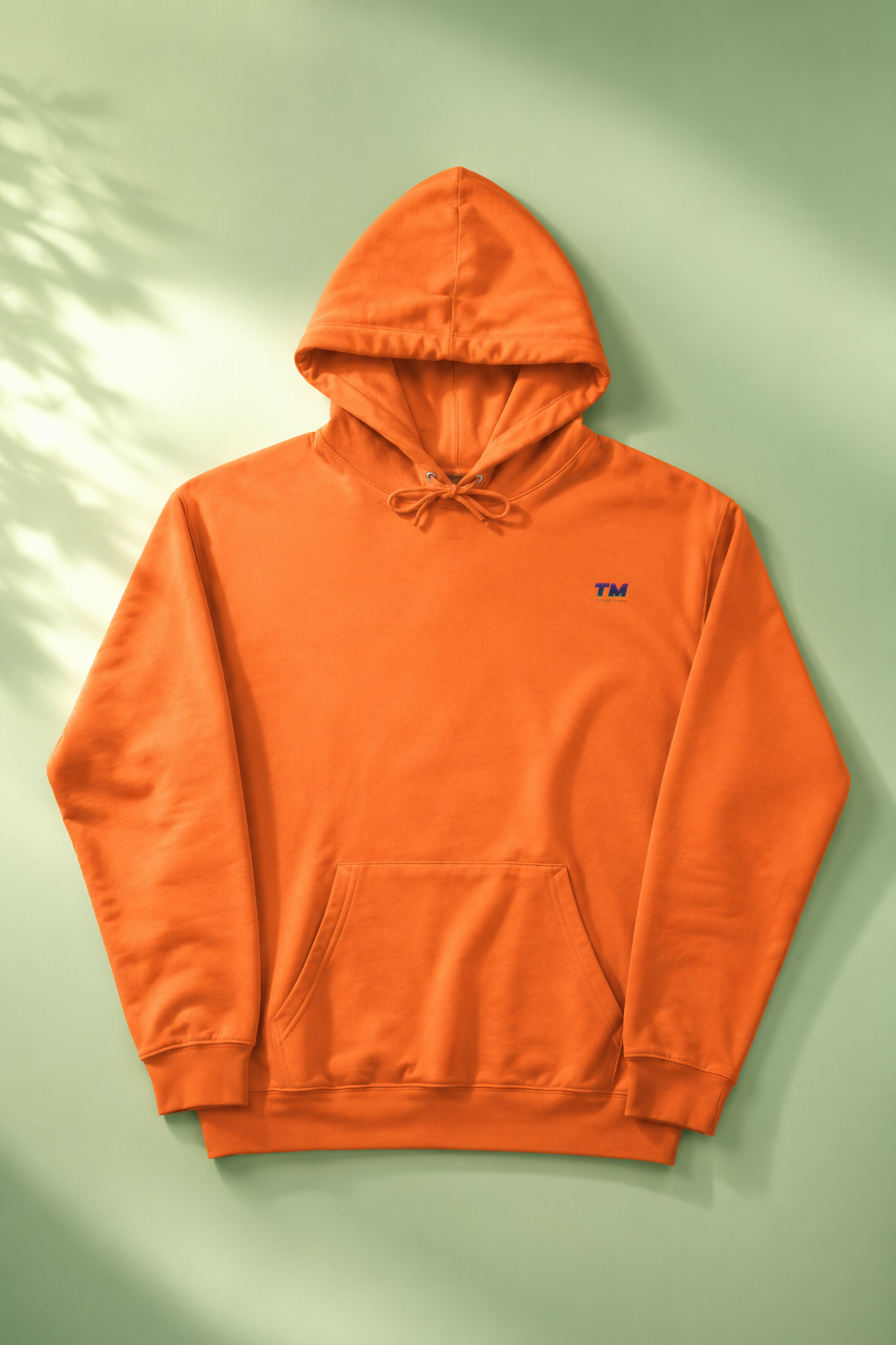 Tantrum Media EcoSmart orange hoodie flat lay on a soft pastel green background.