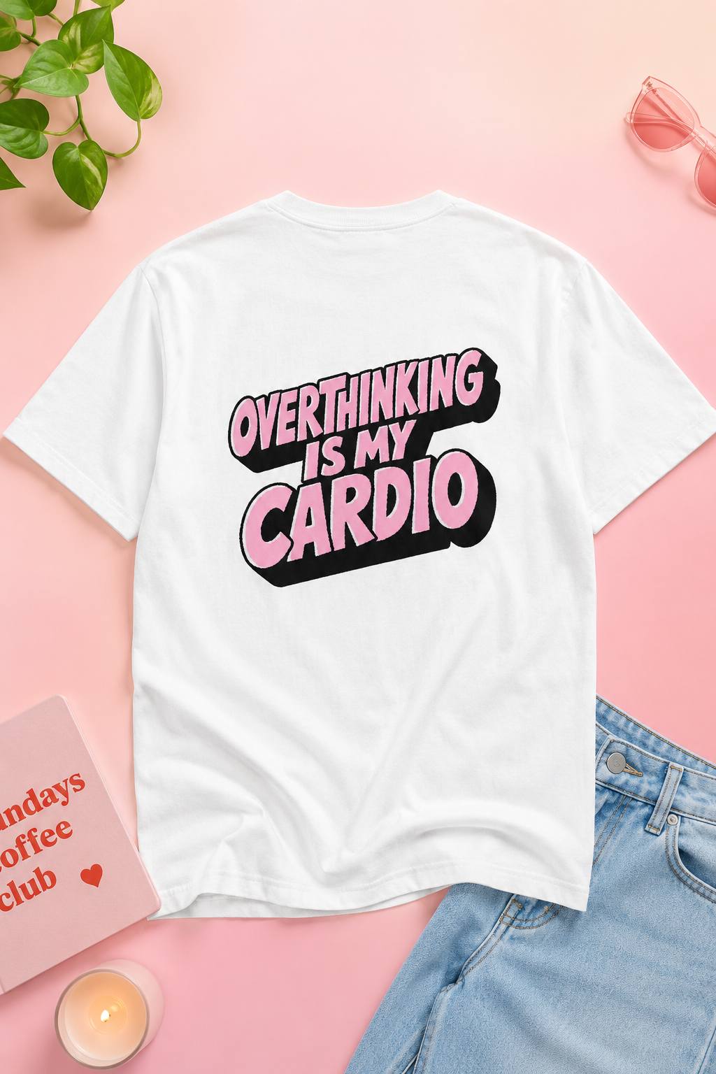 Flat lay of Overthinking Is My Cardio graphic T-shirt back on pastel pink background