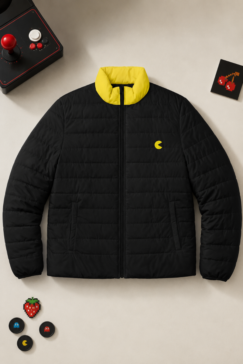 Front flat lay of the black and yellow Pac-Man puffer jacket with retro arcade accessories.