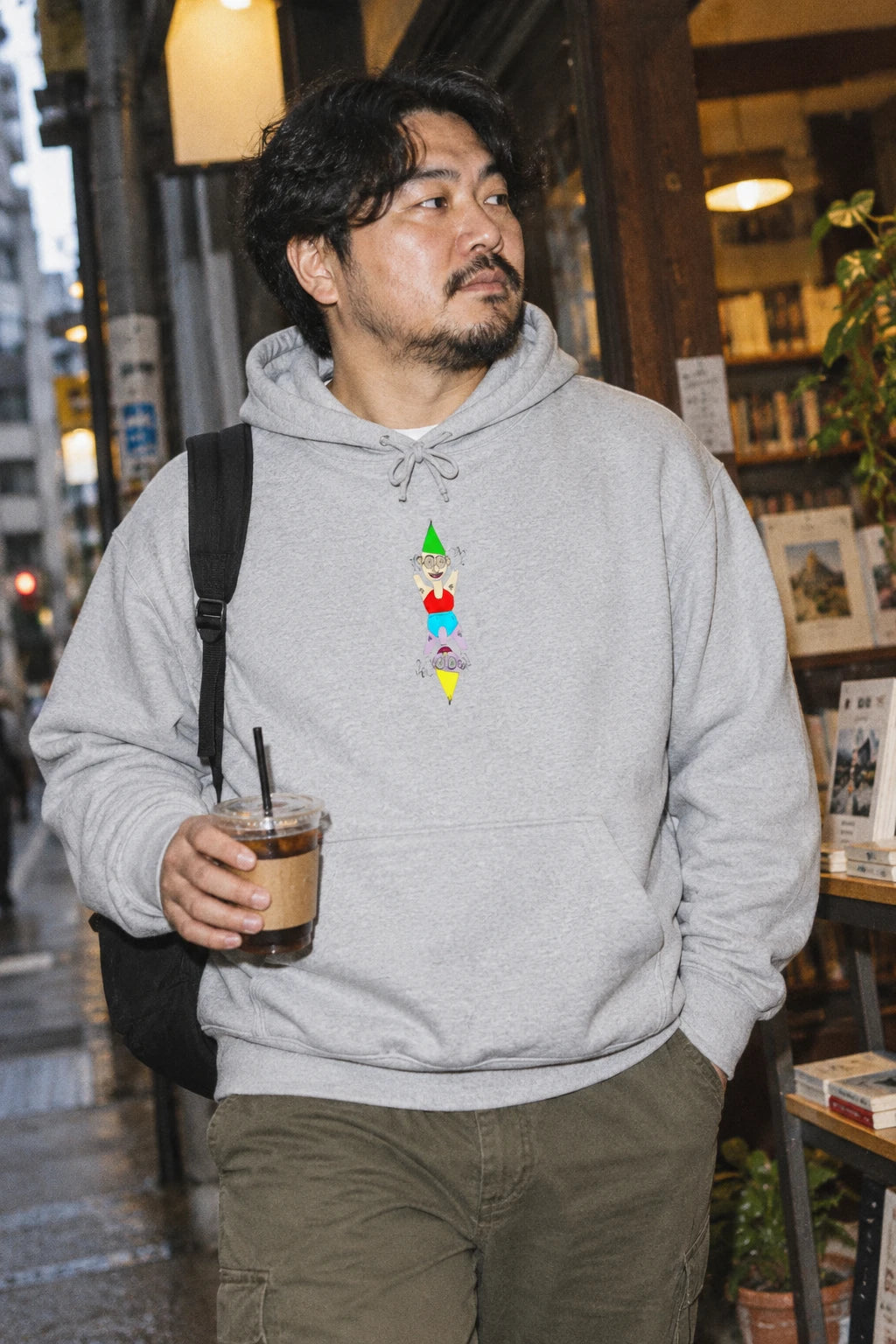 Man wearing the heather gray Party Favor graphic hoodie in an urban bookstore setting