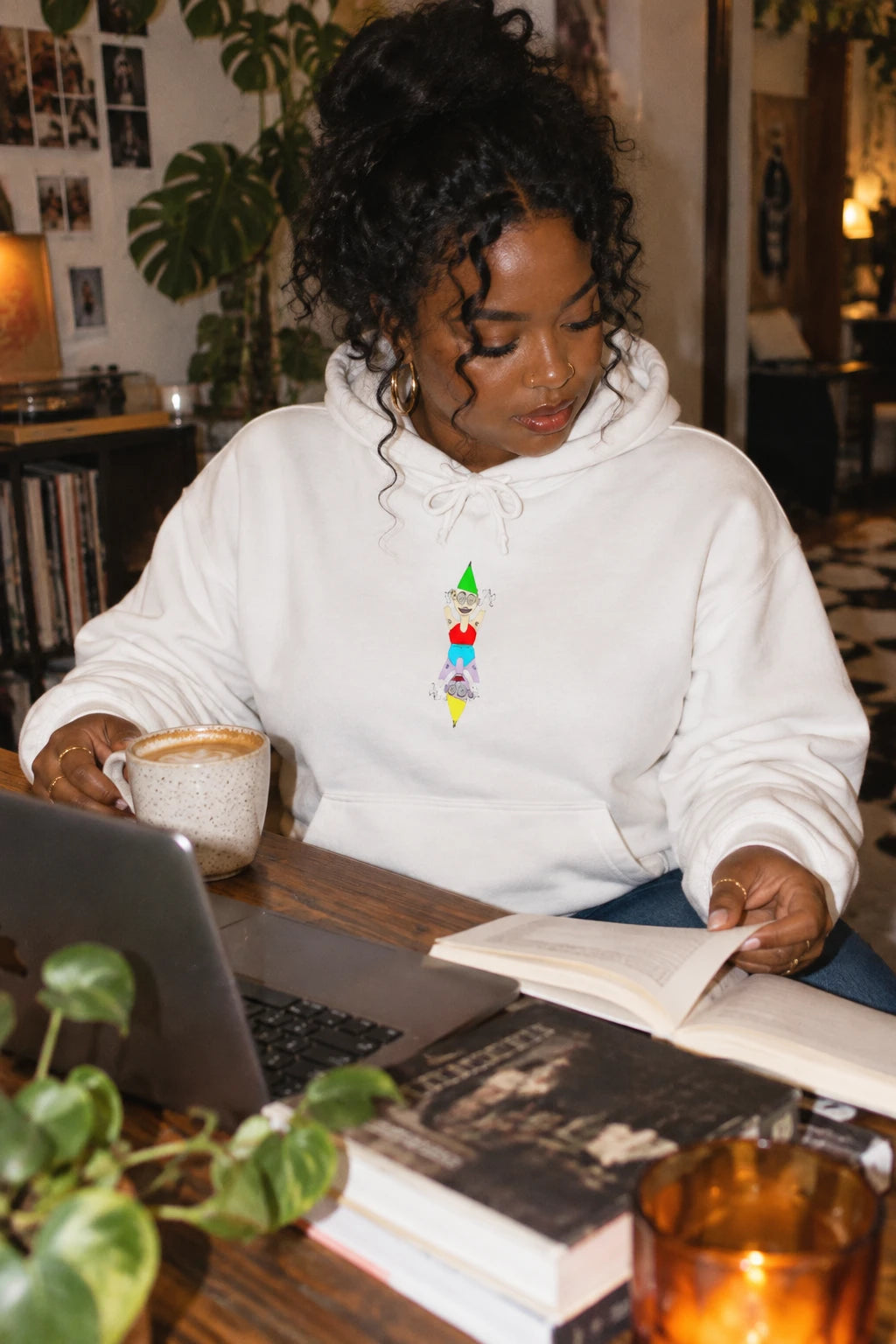 Woman wearing the white Party Favor graphic hoodie while working at a creative workspace