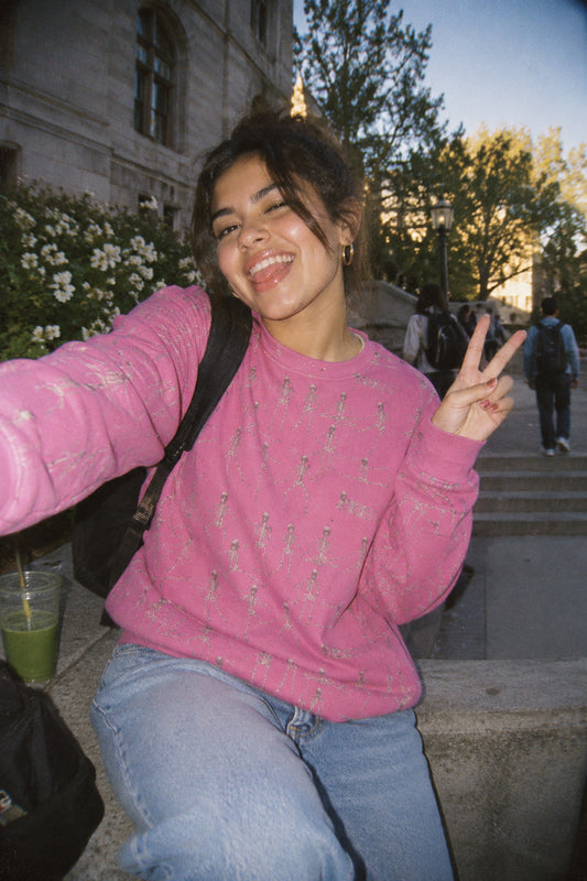 Young woman wearing the Pink Dancing Skeletons Sweatshirt on a college campus