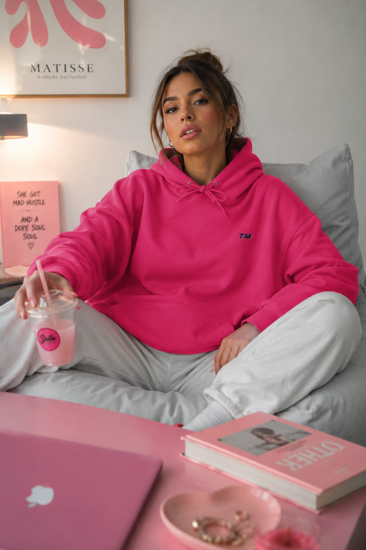Female Gen Z wearing the Tantrum Media EcoSmart pink hoodie relaxing at home in a cozy editorial lifestyle scene.