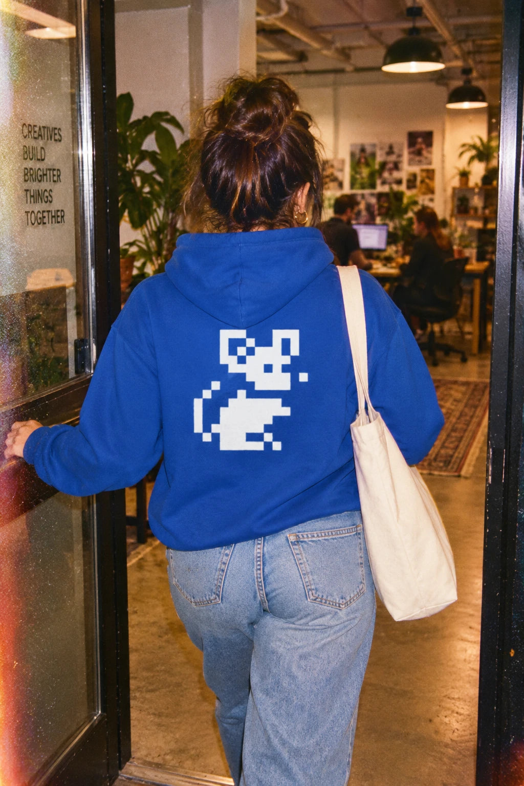 Blue Pixel Mouse Zip Hoodie worn from the back entering a creative office