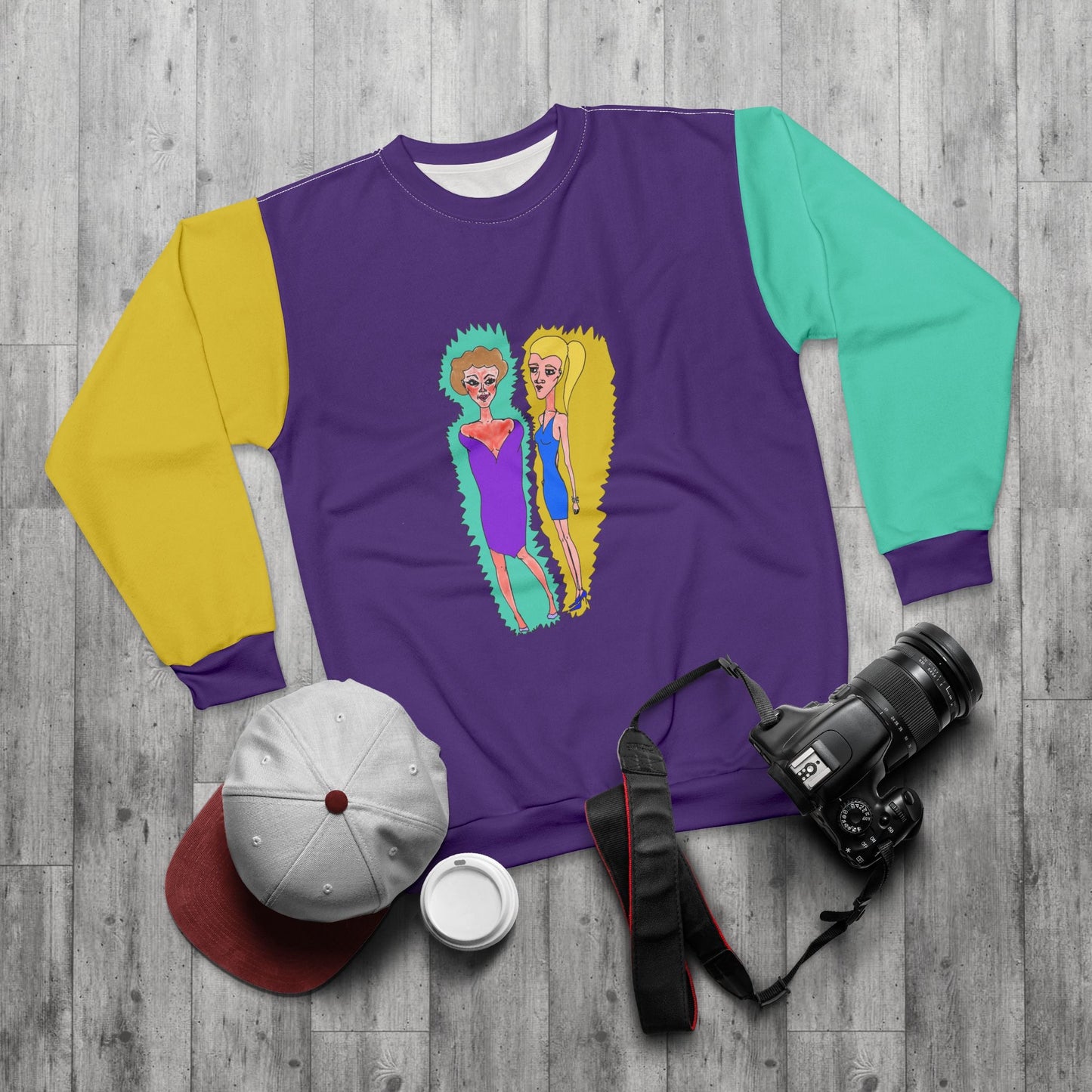 Purple illustrated sweatshirt displayed in a lifestyle flat lay with casual accessories