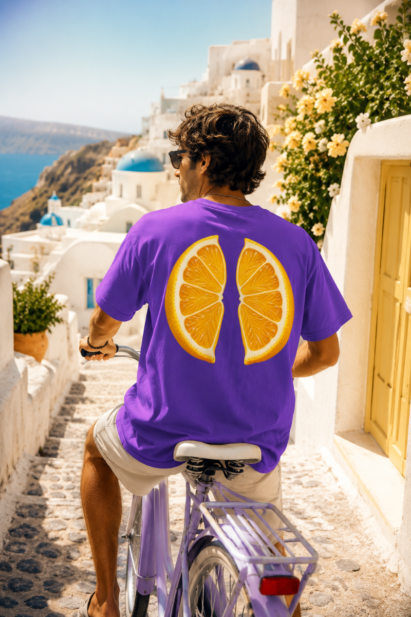 Woman wearing purple lemon back print T-shirt while walking through a sunny orange orchard