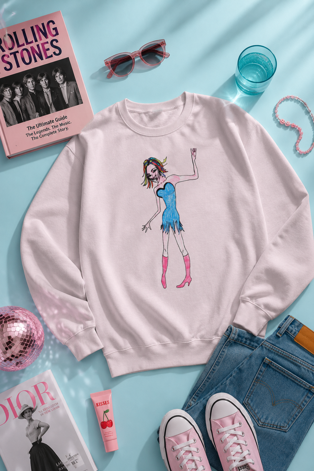 Rainbow Nights Unisex Sweatshirt flat-lay photography mockup on a pastel blue background with original illustrated artwork and lifestyle accessories.