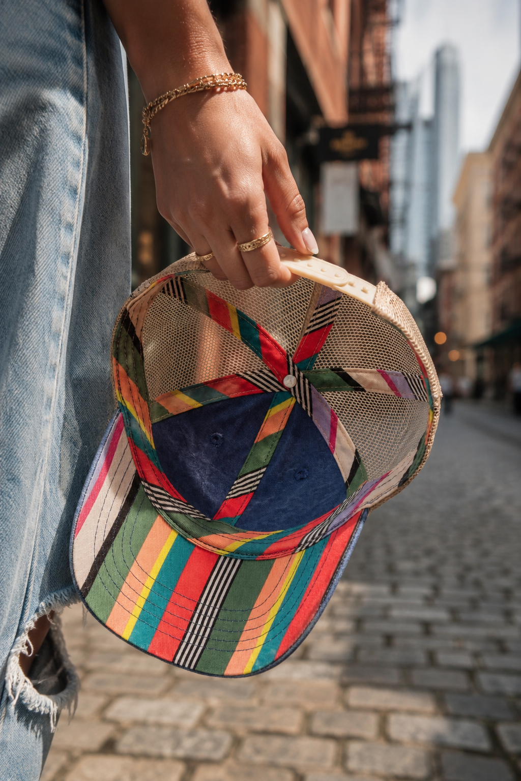 Rainbow striped mesh trucker hat carried through the city.