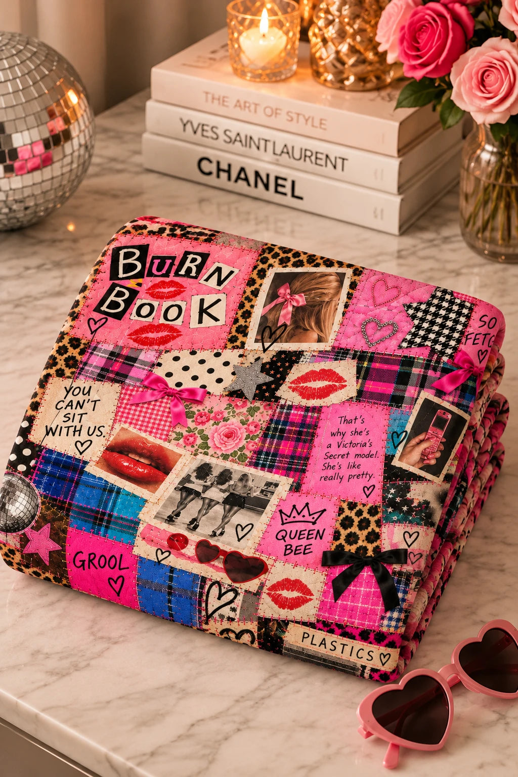 Folded Tantrum Media Regina George Burn Book Sweatshirt Blanket on a marble table, highlighting the pink Burn Book graphic, plaid, leopard print and collage details.