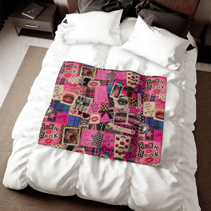 Tantrum Media Regina George Burn Book Sweatshirt Blanket laid across white bedding, featuring a bold pink scrapbook print and Mean Girls-inspired artwork.