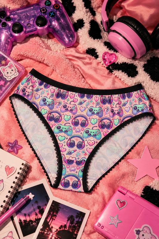 Retro Gamer panties with pastel arcade print, gaming controllers and headphones styled in a colorful flat lay