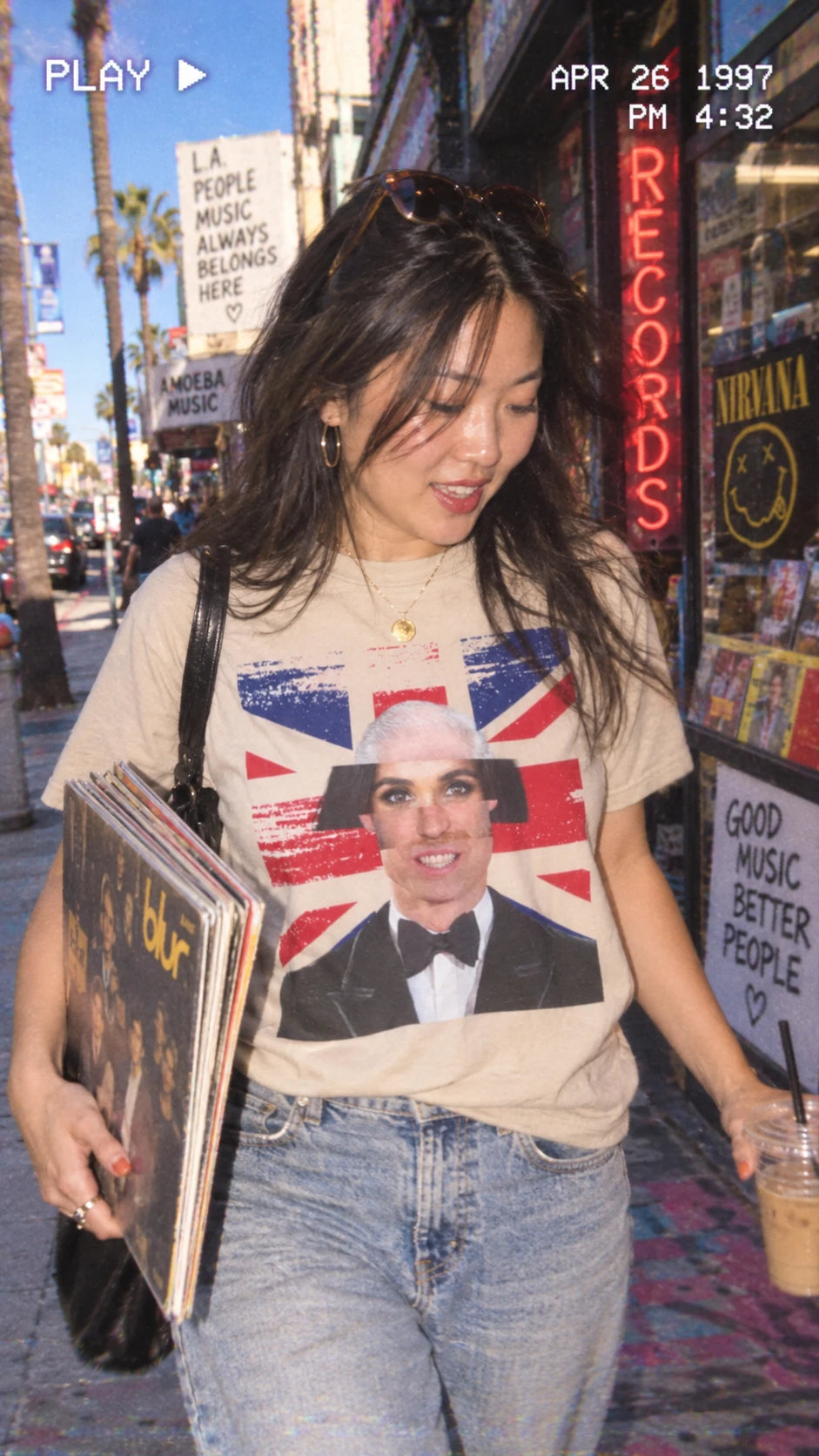Woman wearing the natural Tantrum Media Royal Frankenstein T-Shirt and carrying vinyl records outside a record shop.