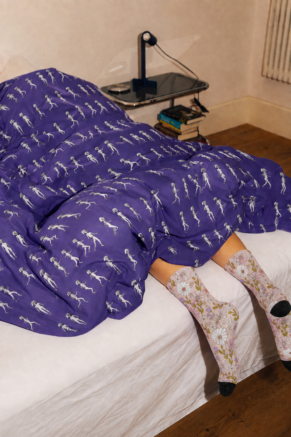 Running Out purple art comforter styled on a bed with floral crew socks in a modern bedroom