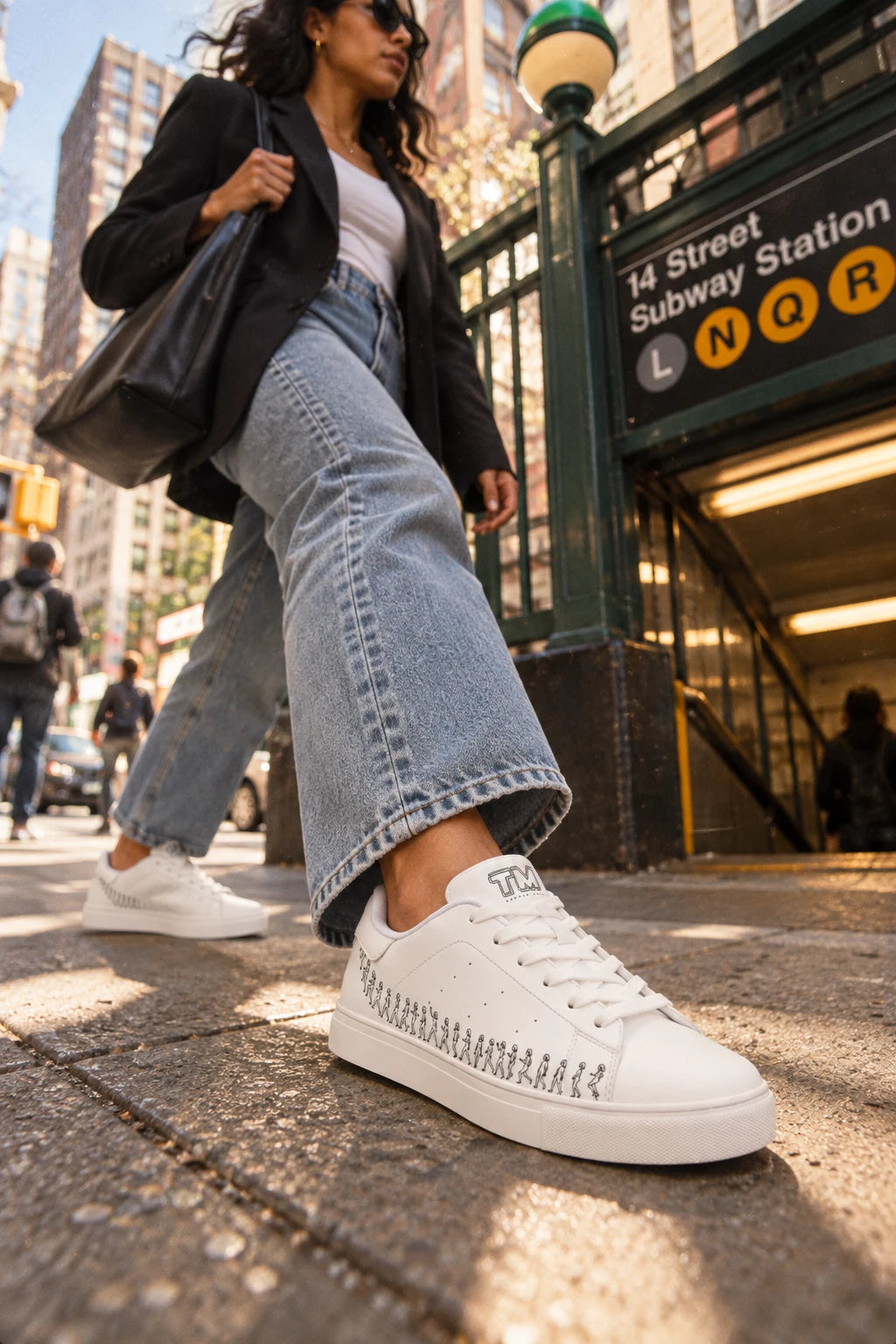 Woman wearing Running Out white leather sneakers near a New York City subway entrance