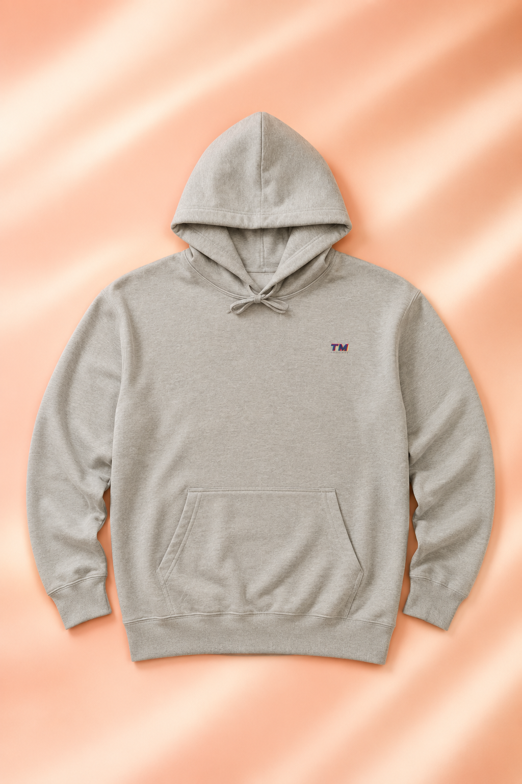 Tantrum Media EcoSmart sand EcoSmart hoodie flat lay on a soft pastel peach background.