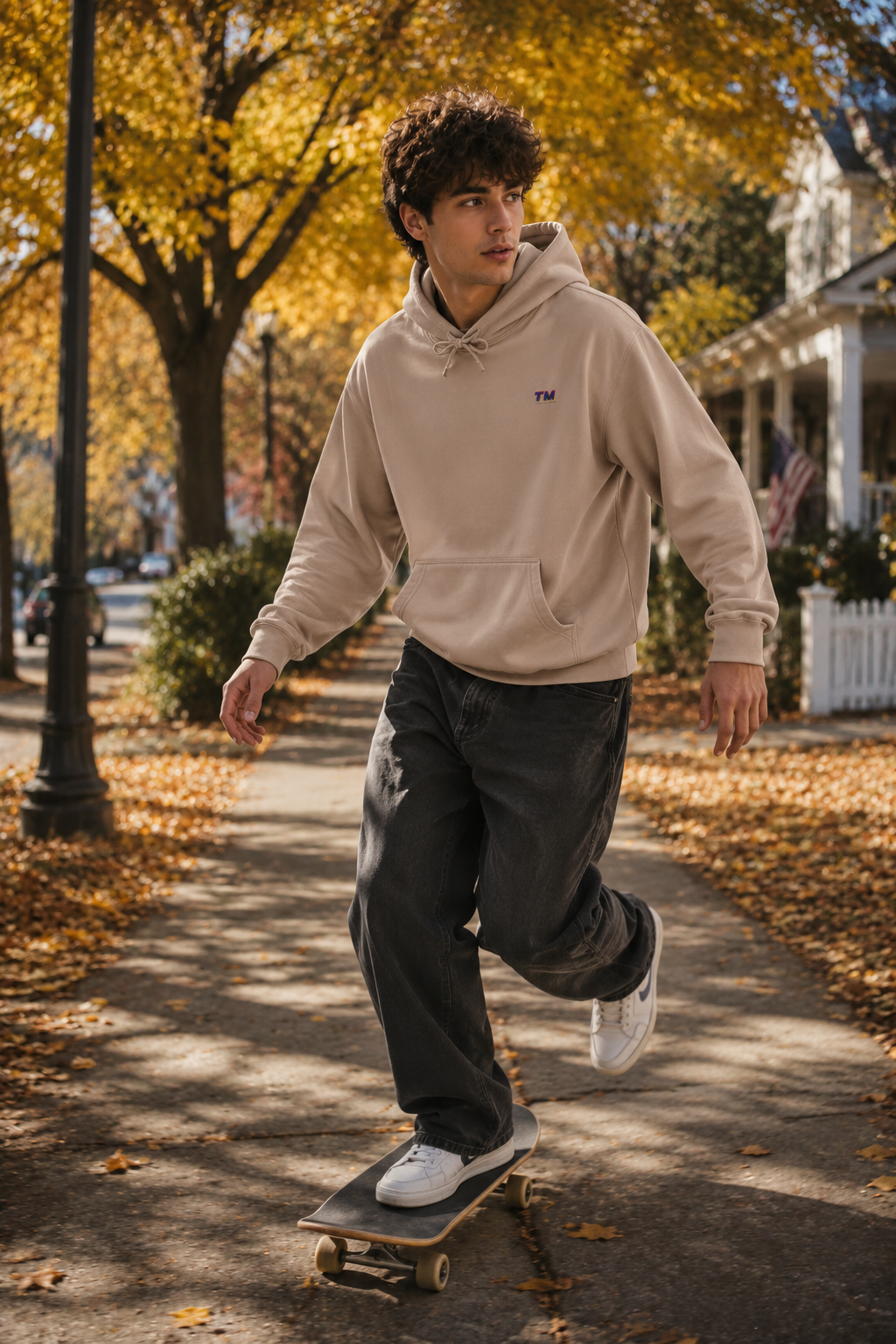 Male Gen Z skateboarding through an autumn street in Westchester wearing the Tantrum Media EcoSmart sand hoodie.
