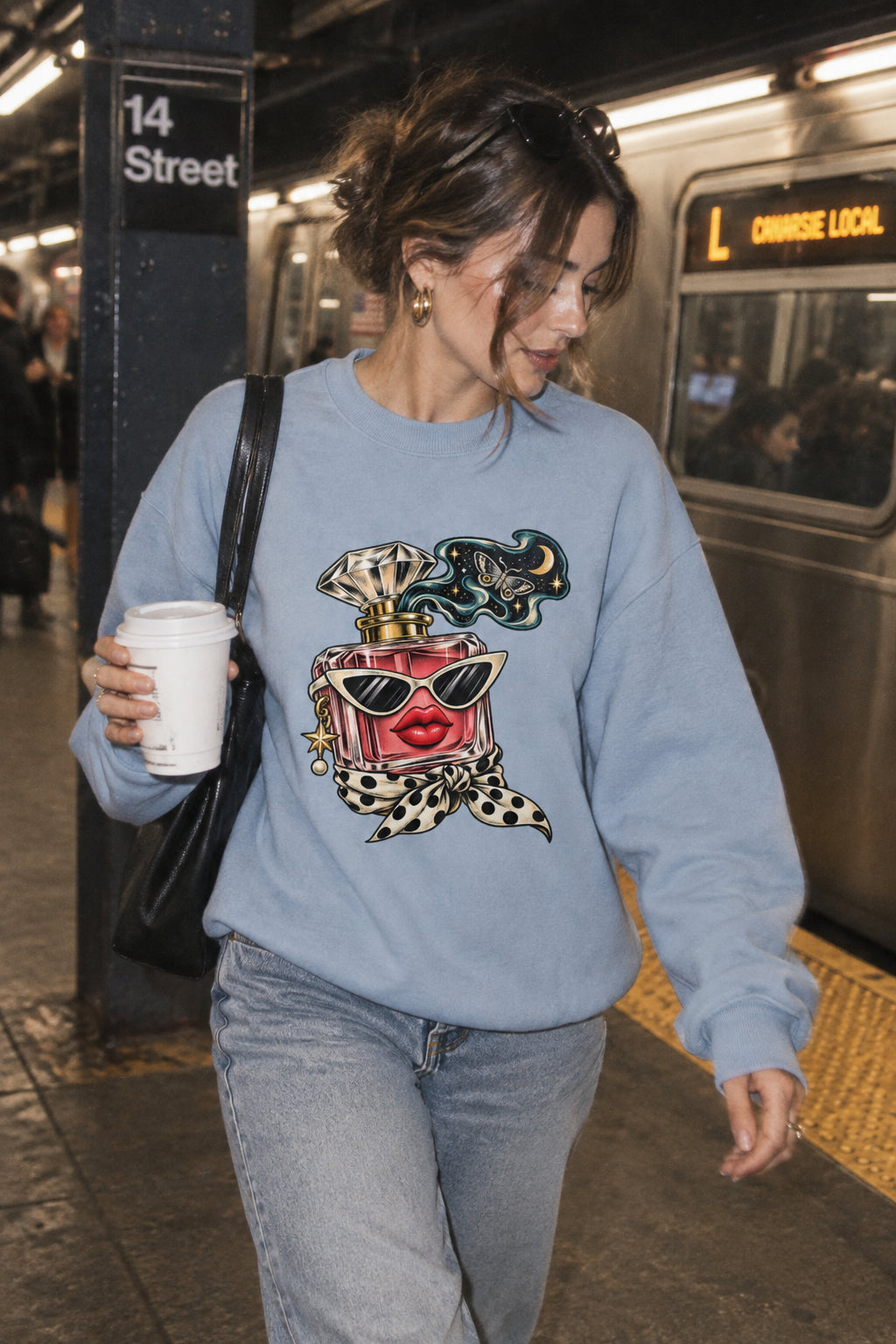 Woman wearing the light blue Scent of Chaos graphic sweatshirt with casual jeans while walking through a New York City subway station.