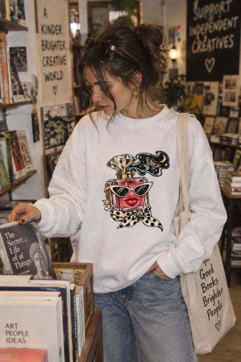 Woman wearing the white Scent of Chaos graphic crewneck sweatshirt while browsing books in an independent bookstore.