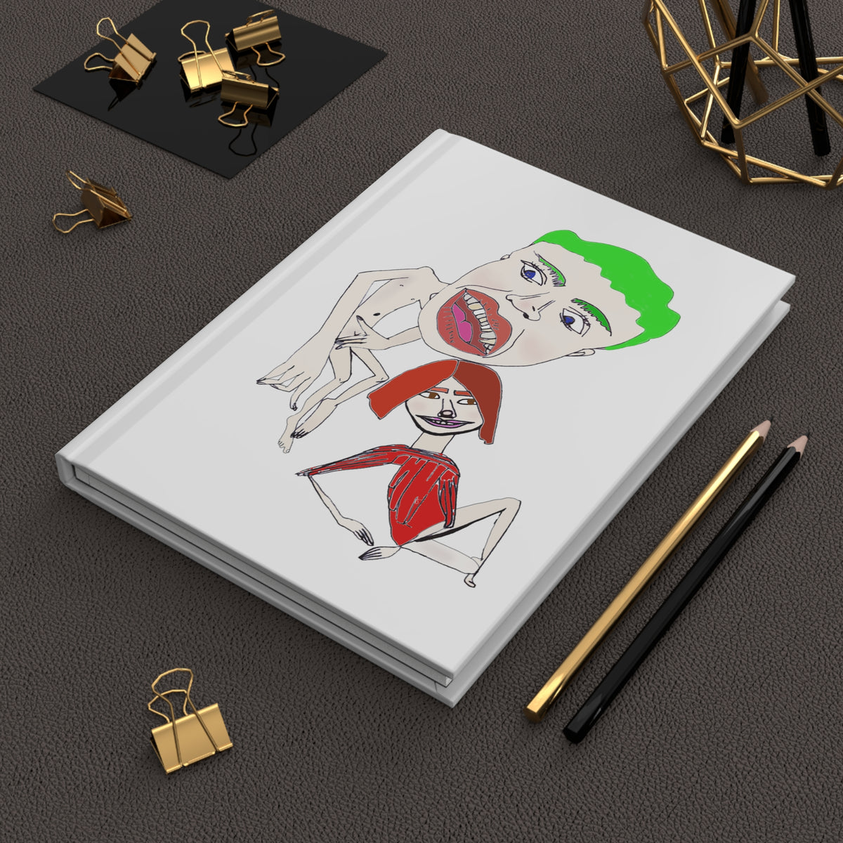 Scramble illustrated hardcover journal styled on a dark desk with pens and creative accessories