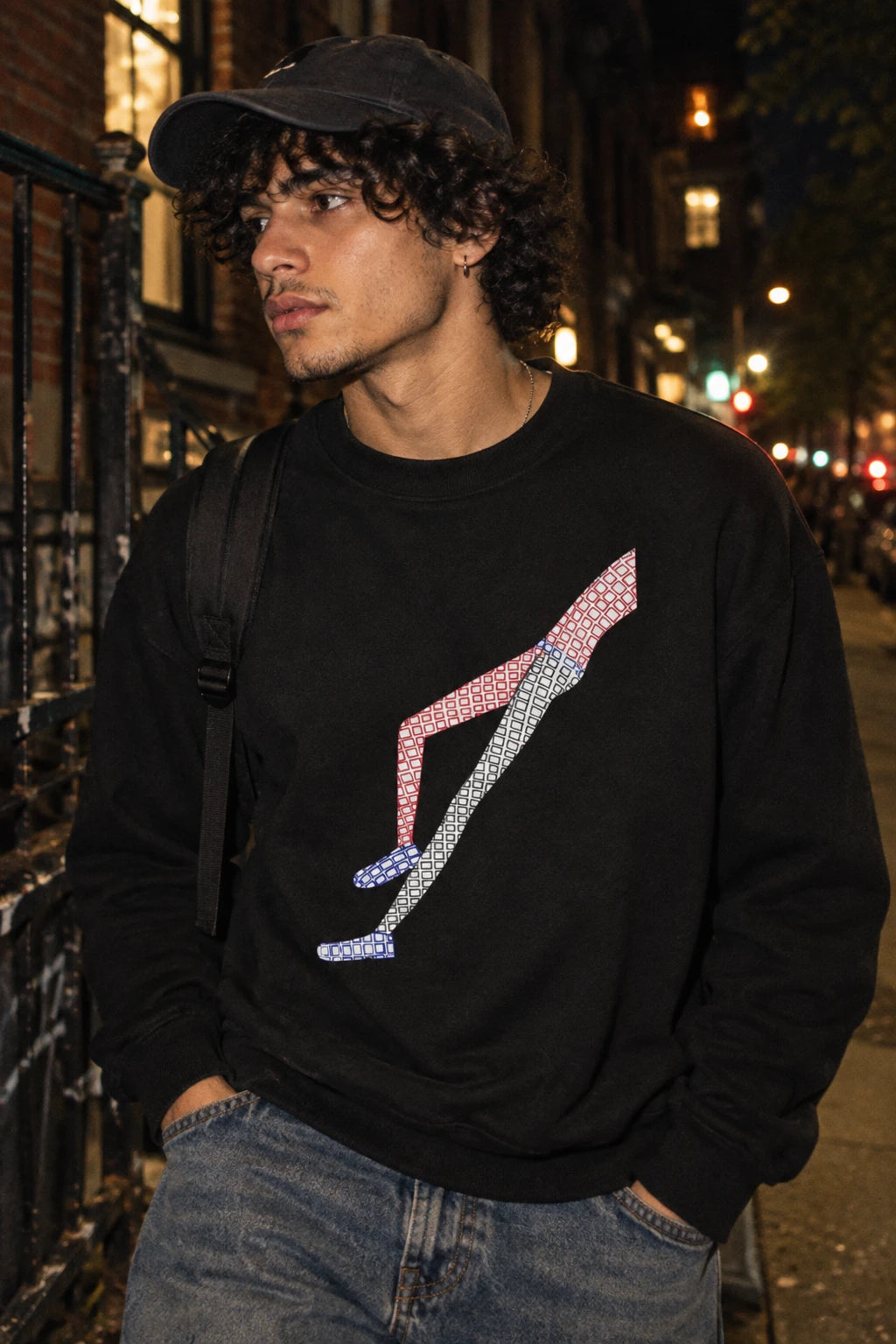Young man wearing the black Shapes in Shapes abstract art sweatshirt in a nighttime urban setting.