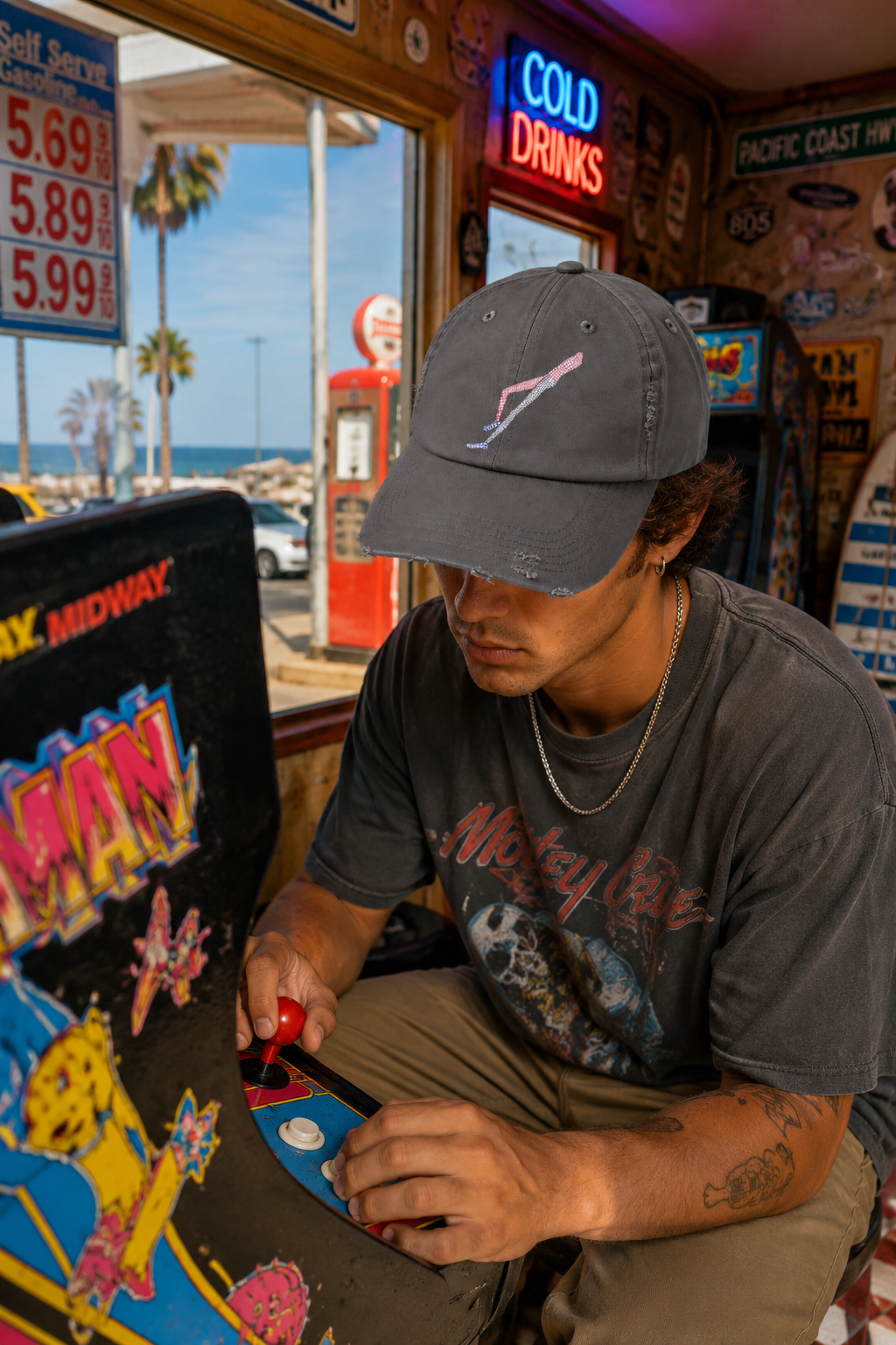 Gen Z male wearing Shapes in Shapes grey distressed baseball cap while playing arcade games in a colorful coastal town setting.