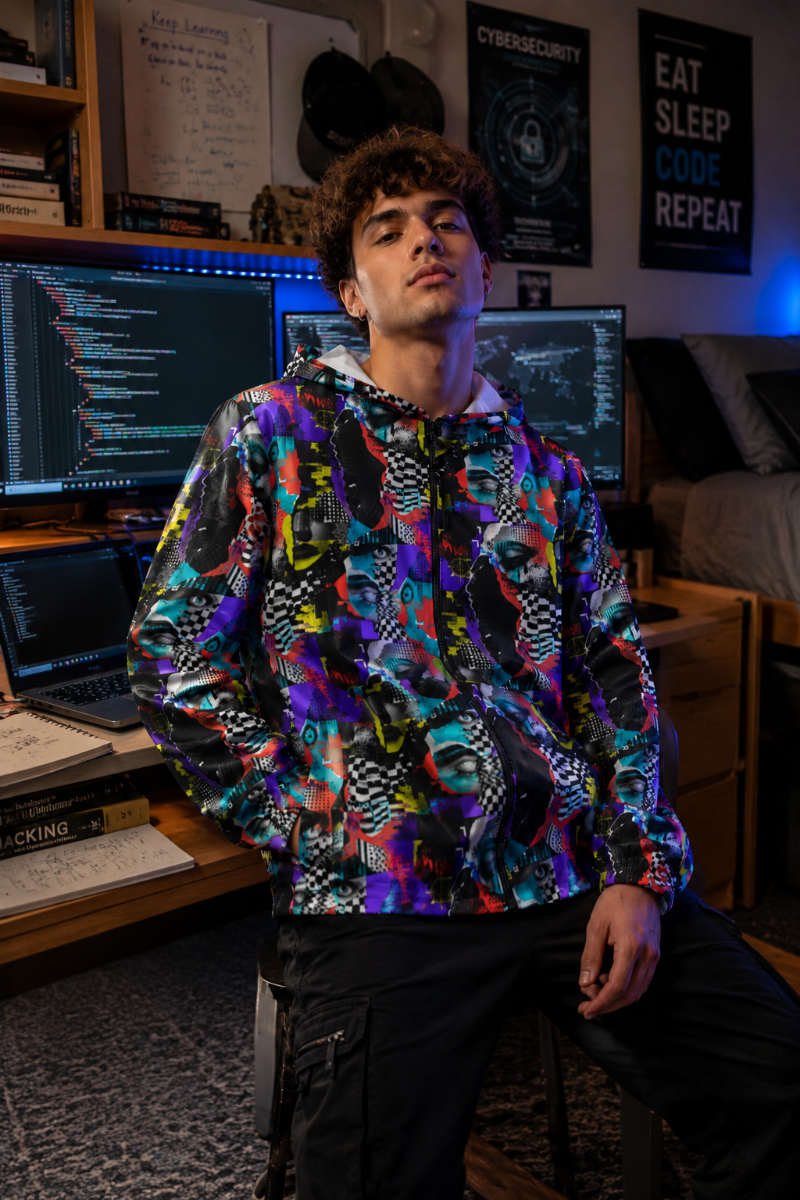 College cybersecurity student wearing the Signal Scramble adversarial fashion windbreaker in a tech dorm room