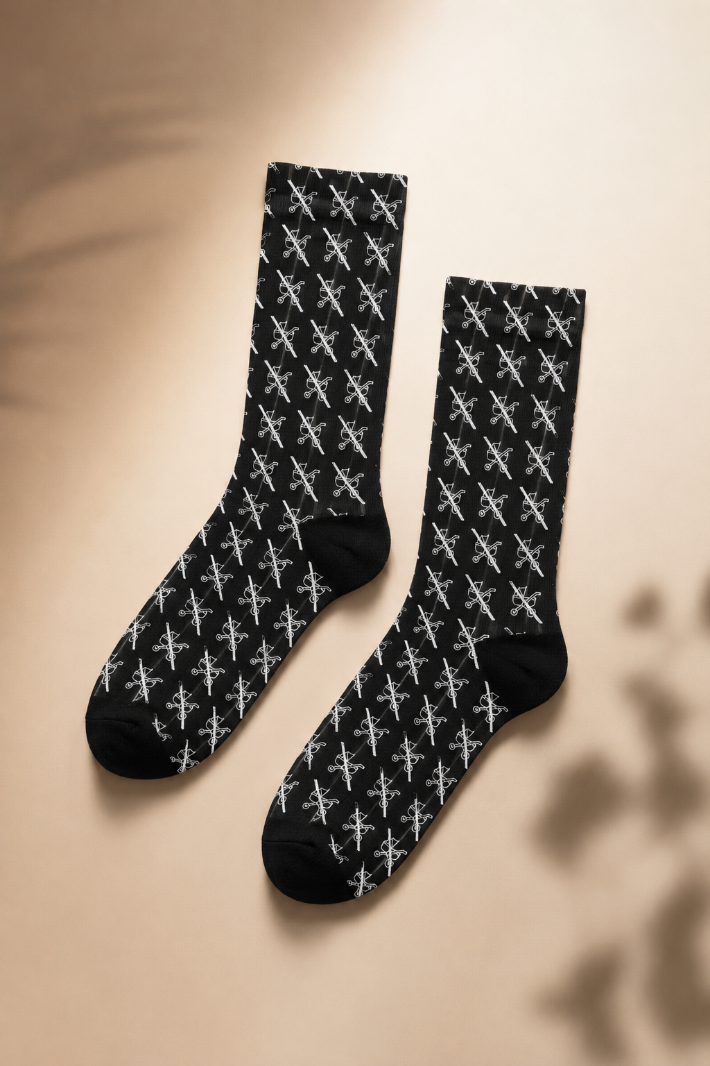 Cinematic editorial flat lay of black crew socks with repeating white scissors pattern on a soft neutral background.