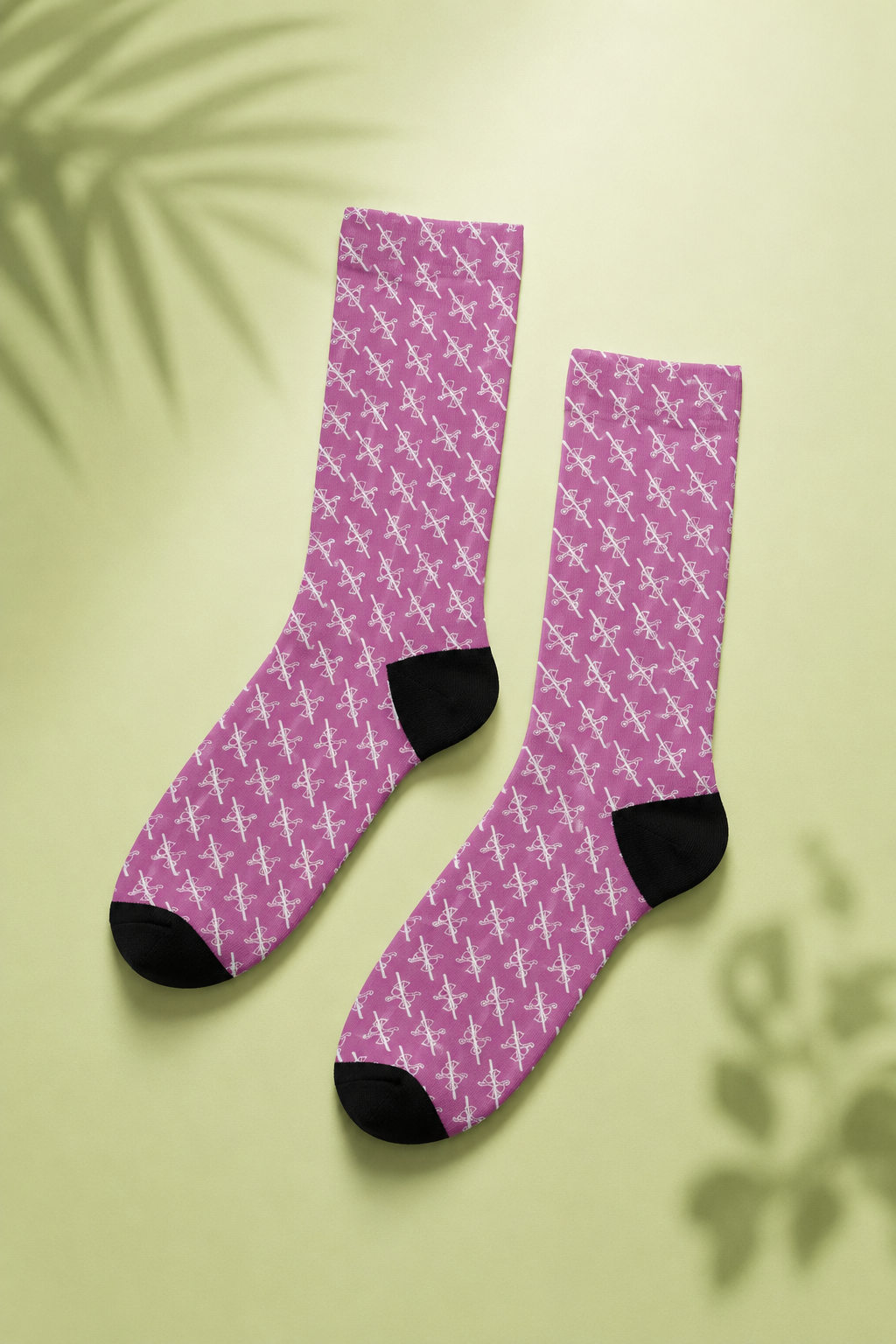 Cinematic flat lay of pink crew socks featuring an all-over white scissors pattern on a soft pastel green background.