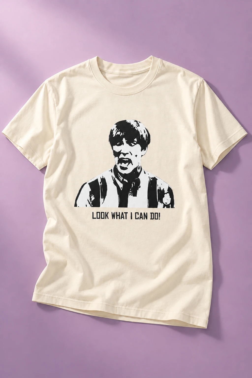 Natural white Tantrum Media Stuart MadTV Unisex T-Shirt laid flat on lilac, showing the portrait and printed catchphrase.