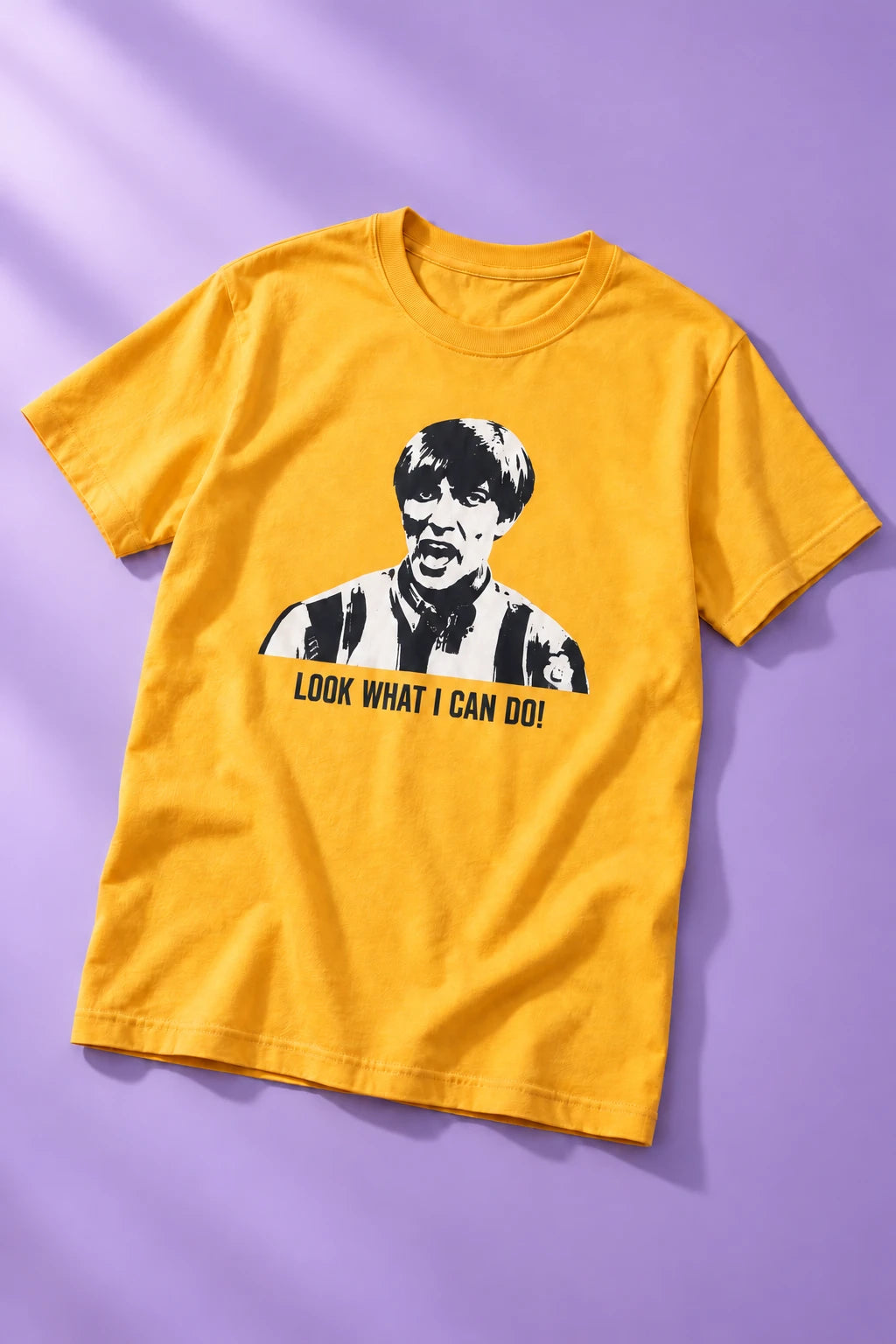 Golden yellow Tantrum Media Stuart MadTV Unisex T-Shirt laid flat on lavender, displaying the portrait and catchphrase.