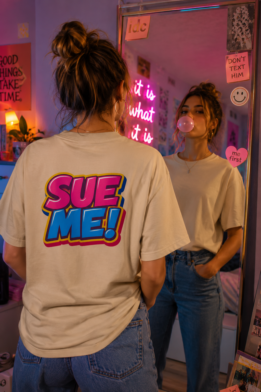 Gen Z woman wearing SUE ME back graphic T-shirt while blowing bubblegum in mirror