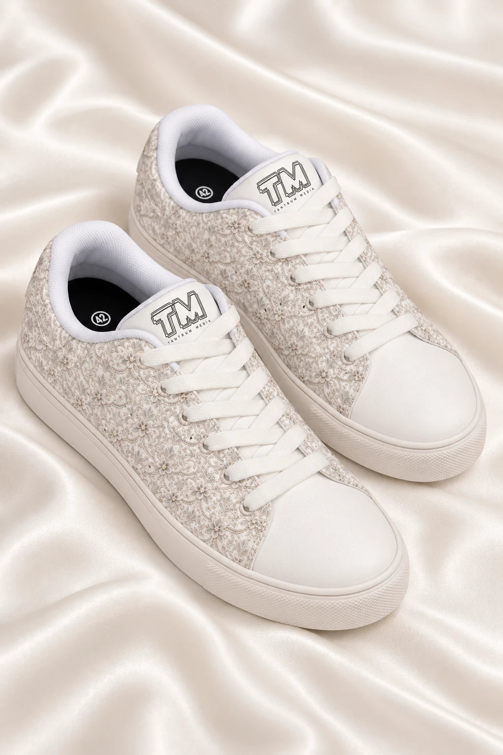 Angled flat lay of Tantrum 04 women’s bridal lace wedding sneakers on ivory satin