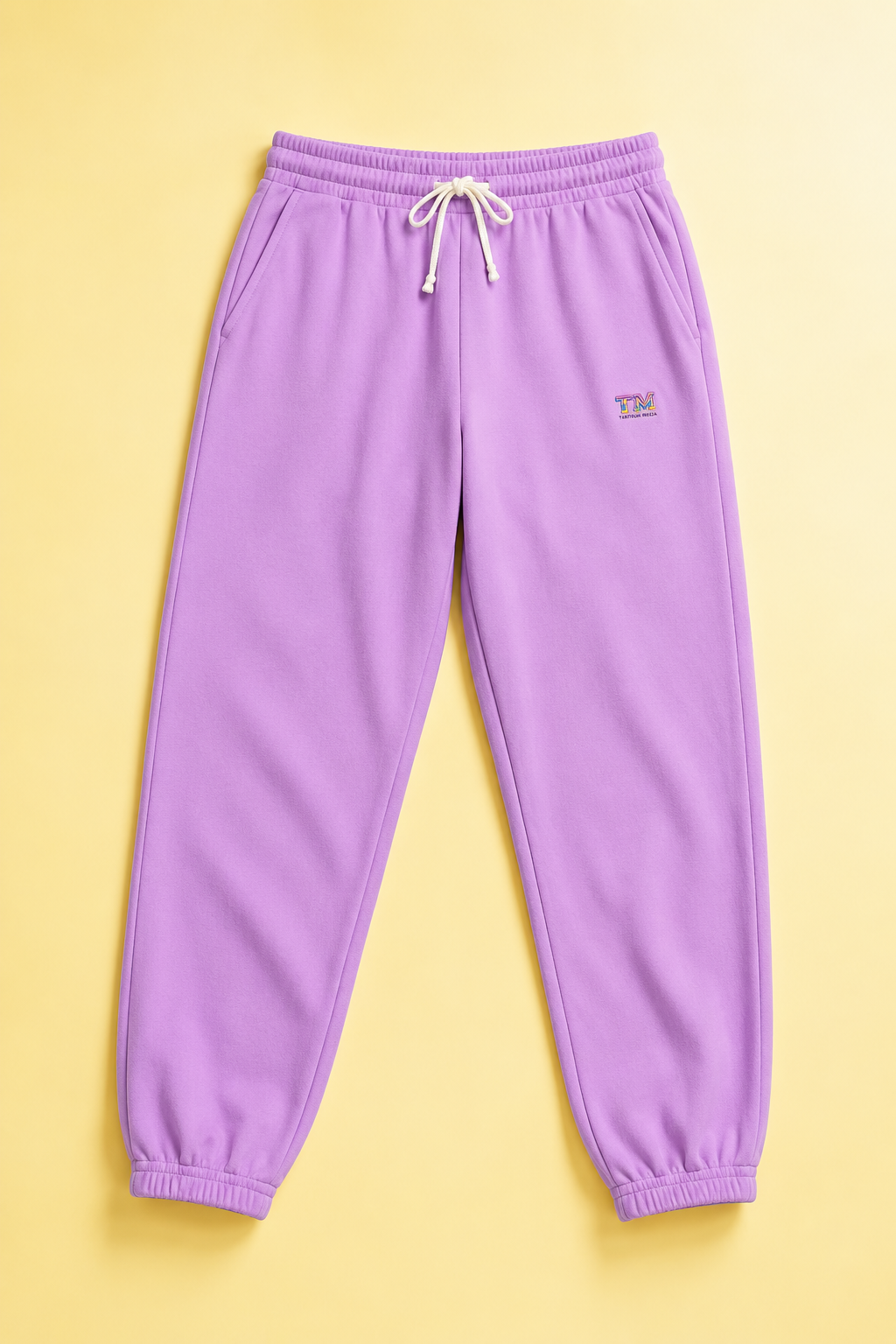 Lavender Tantrum Media sweatpants flat lay on a soft pastel yellow background.