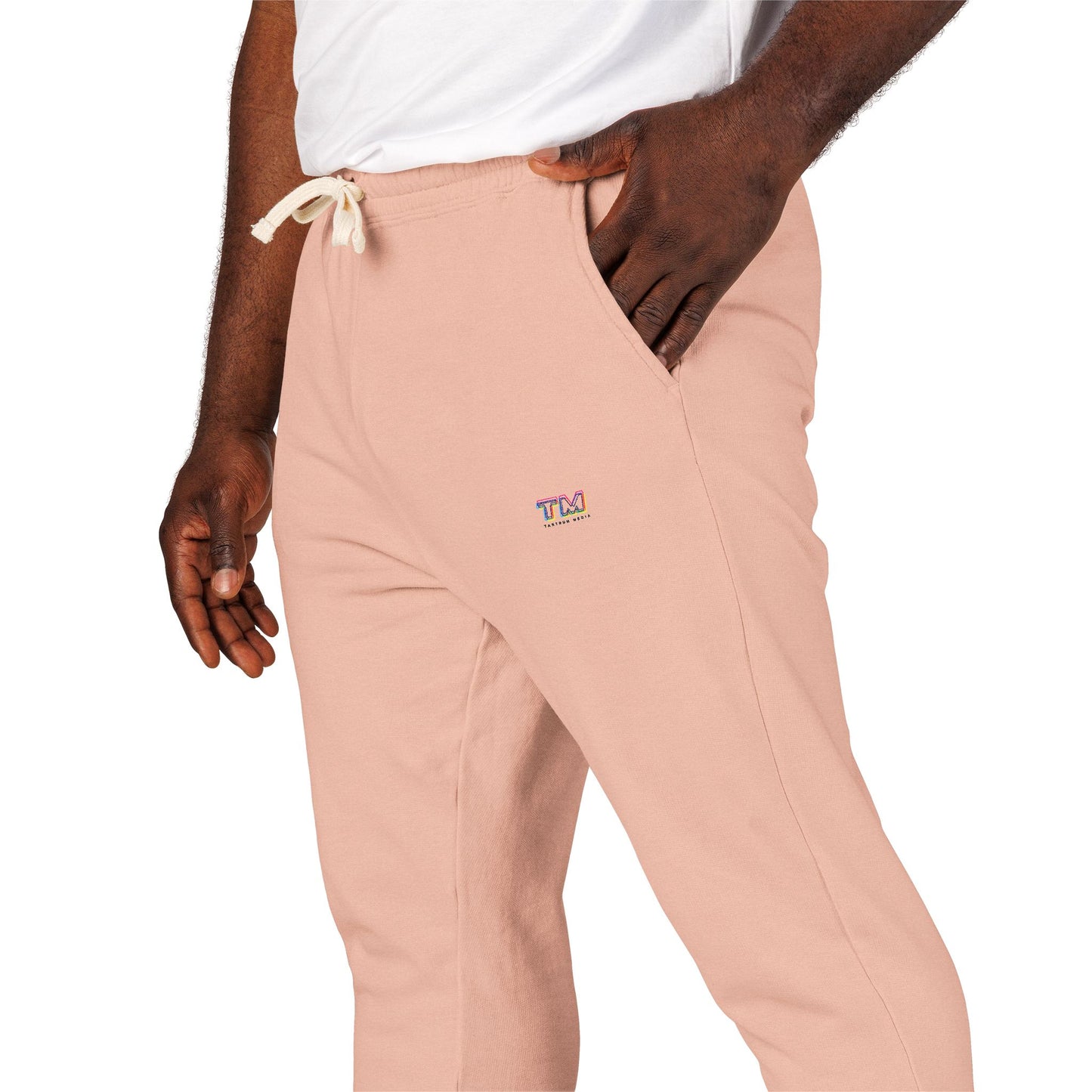Close-up detail of peach Tantrum Media fleece sweatpants with embroidered logo.