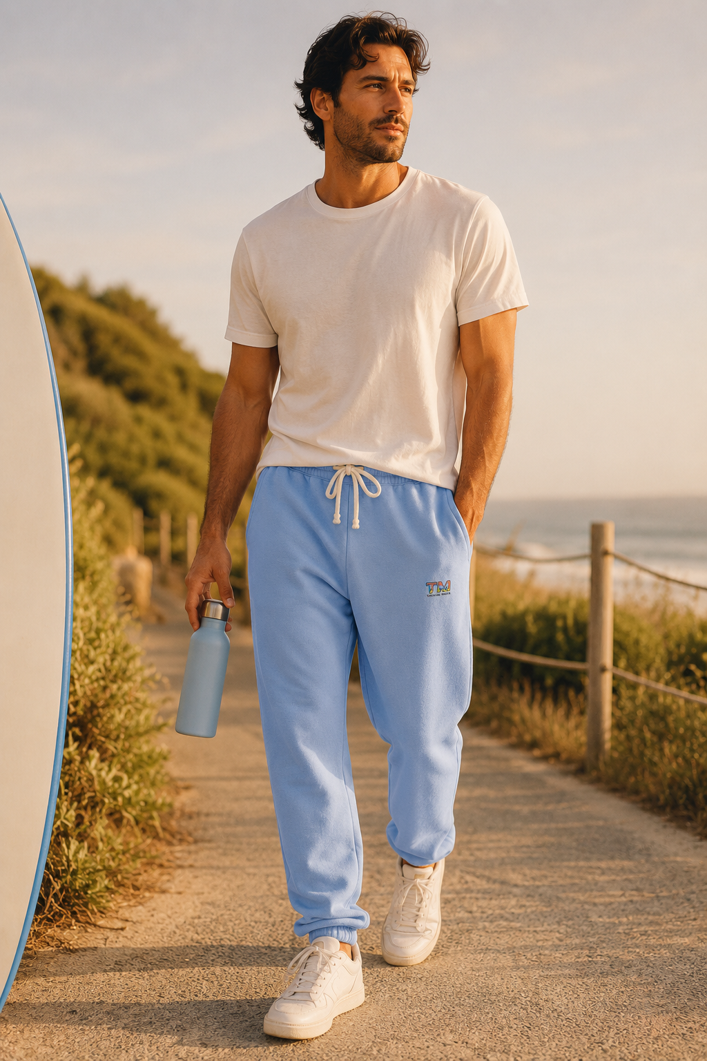Millennial wearing sky blue Tantrum Media sweatpants during a coastal outdoor walk.
