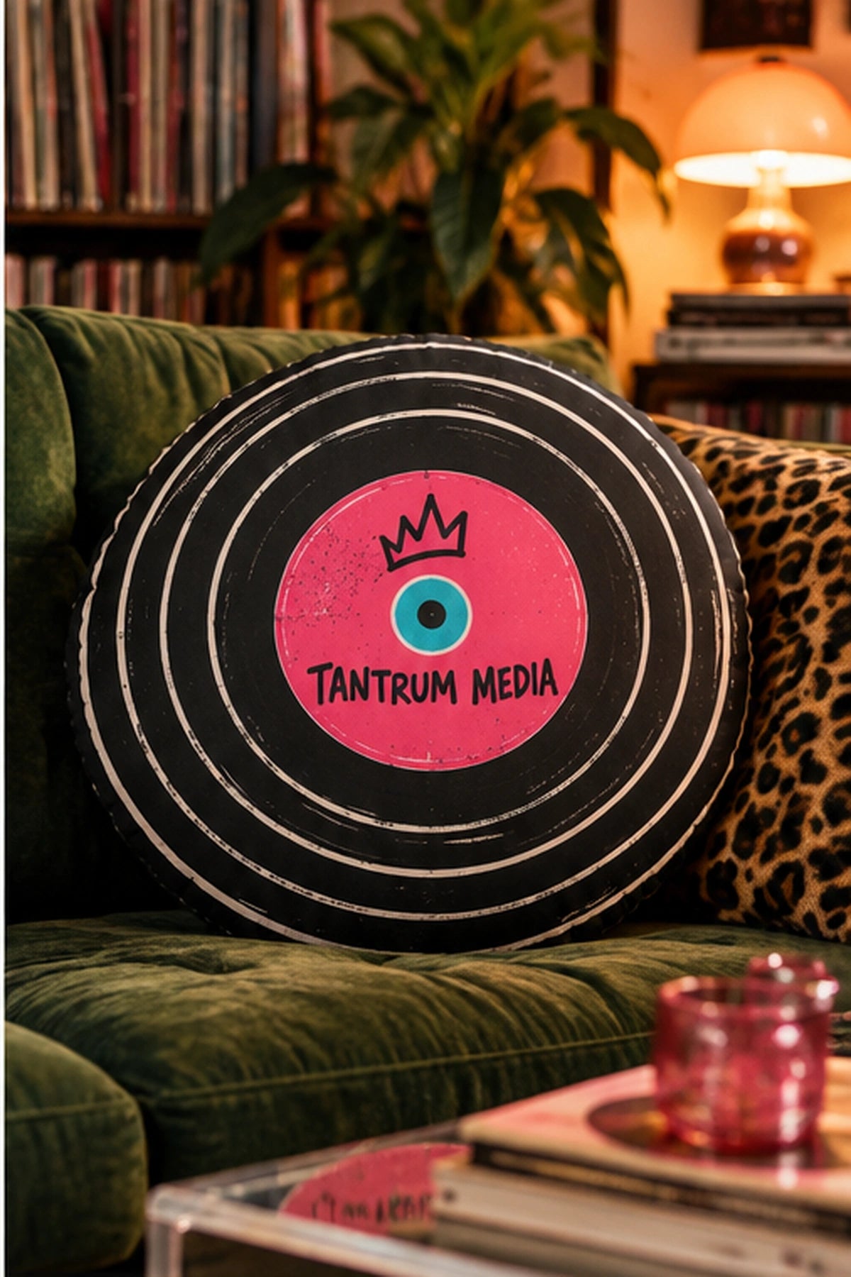 Tantrum Media LP Record Pillow displayed on a green velvet sofa with vintage records and warm lighting, styled as retro music room decor.