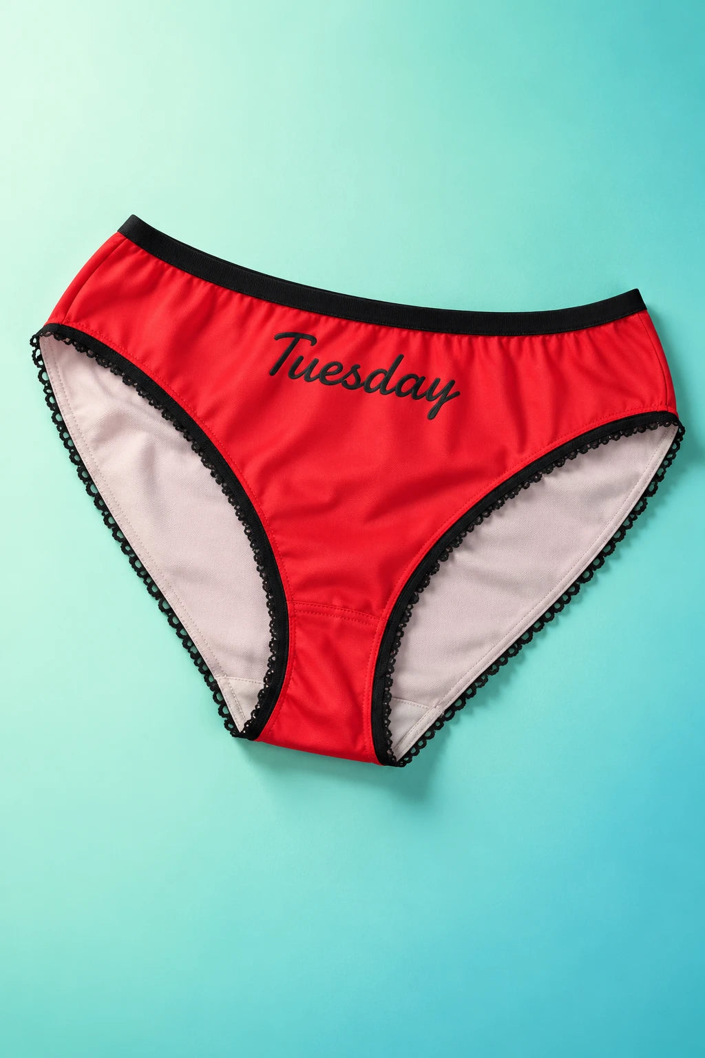 Tantrum Media Tuesday Panty in red with black Tuesday script and scalloped trim, laid flat on a mint and aqua gradient background.