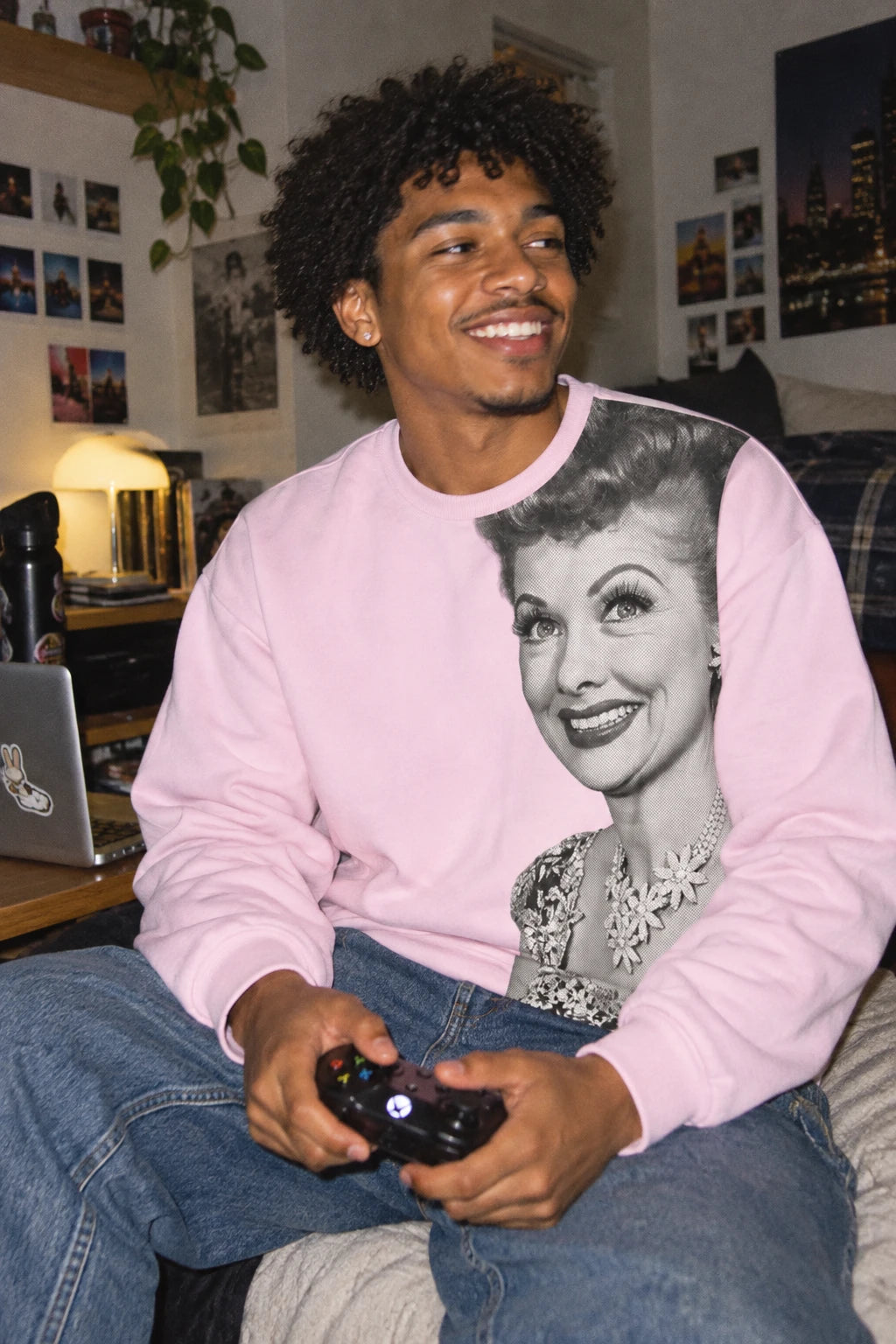 Gen Z man wearing pink Lucille Ball graphic sweatshirt while gaming in an apartment