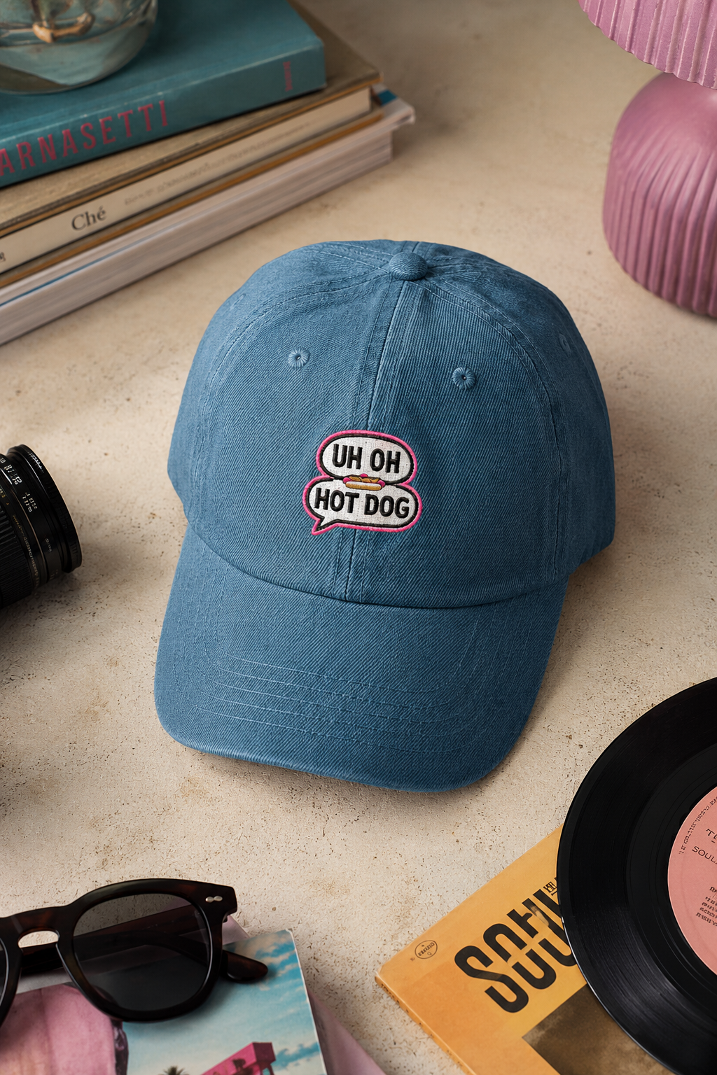 Light blue UH OH HOT DOG embroidered denim dad hat flat lay with pastel accessories