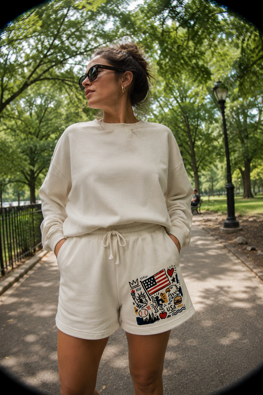 Woman wearing ivory USA artsy unisex sweat shorts with patriotic graphic artwork in park