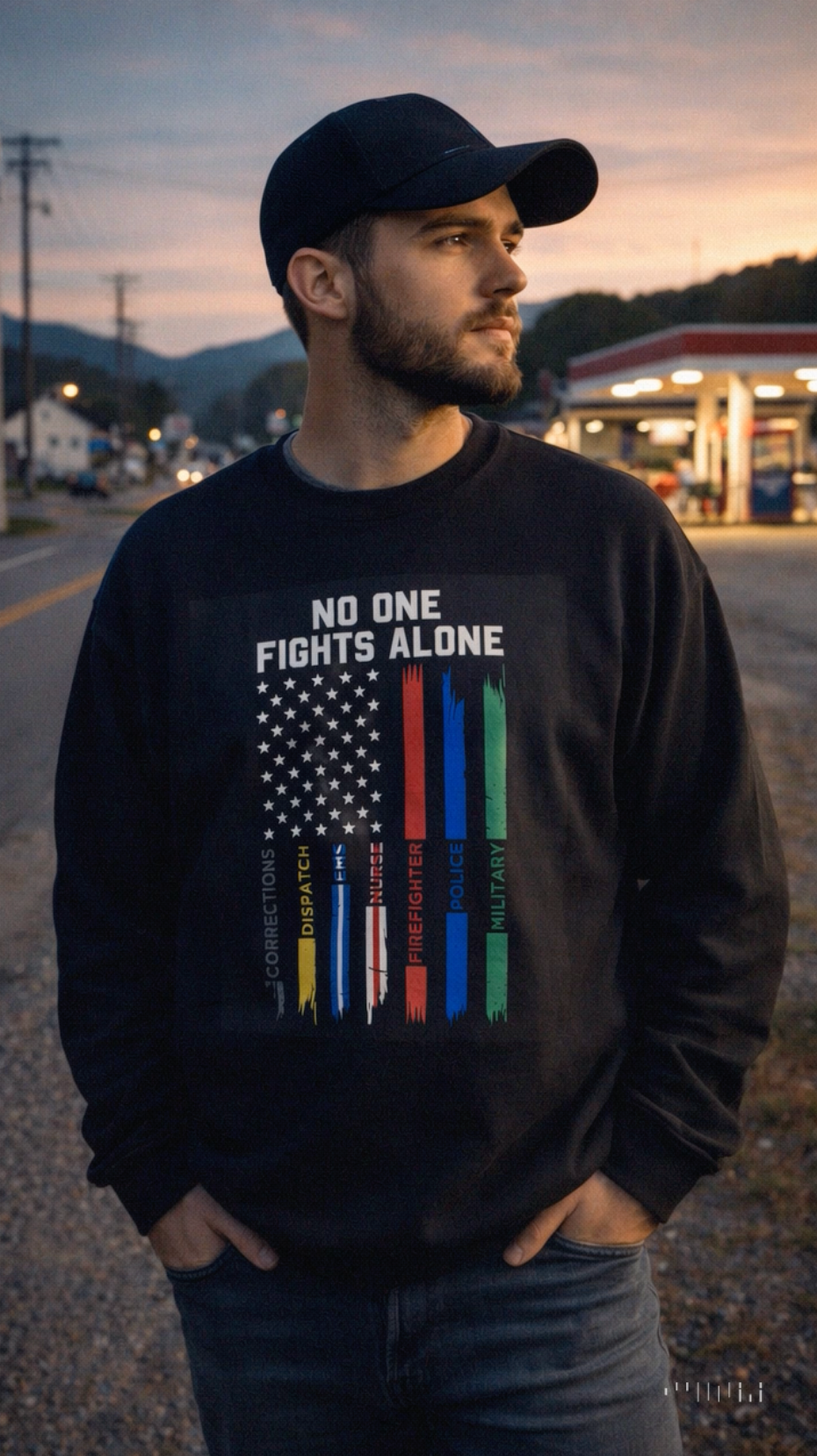 Male model wearing black patriotic Veterans Day sweatshirt outdoors at sunset.
