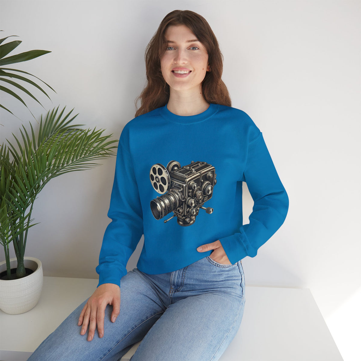 Female model seated, wearing royal blue Film Camera Sweatshirt with camera graphic.