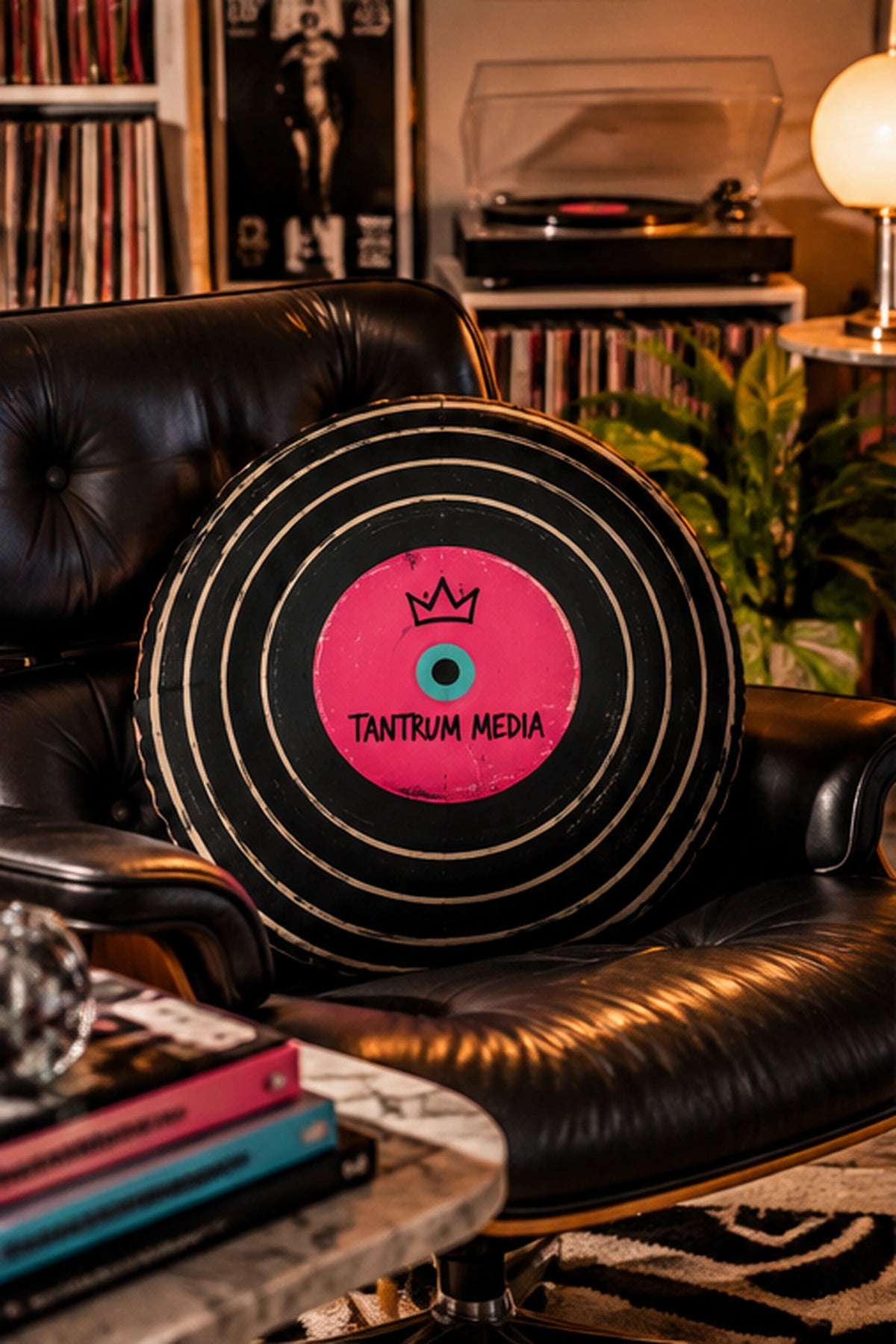 Tantrum Media LP Record Pillow resting on a black leather lounge chair beside a record player and vinyl collection in a retro music room.